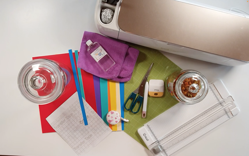 Supplies I used to add vinyl to a glass jar: Cricut, Standard grip mat, self adhesive vinyl, cricut portable trimmer, transfer tape, tape measure, Glass jar, cloth, rubbing alcohol, scissors, weeding tool, burnishing tool,