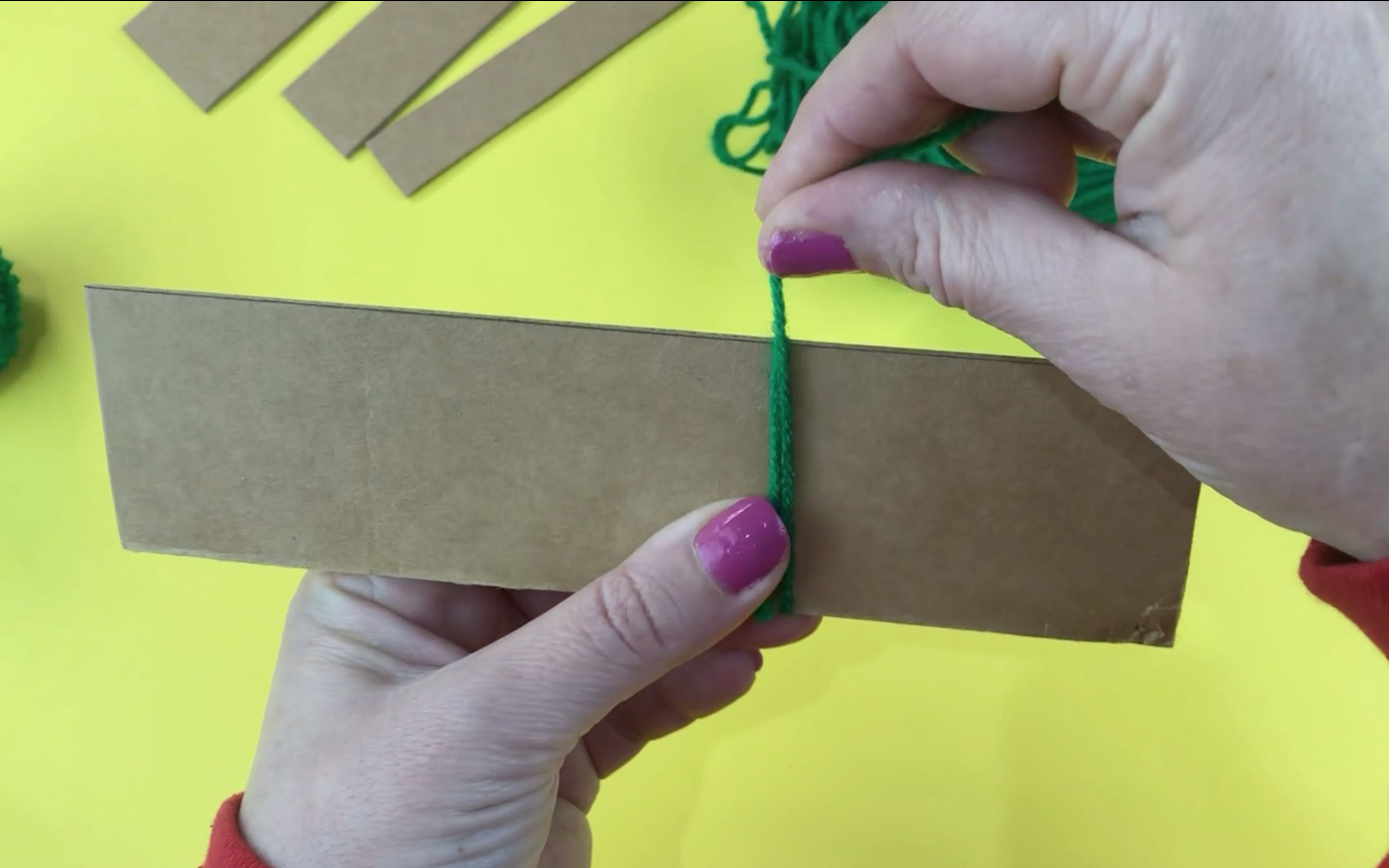 A piece of cardboard 5cm wide with wool being wrapped around it.                   