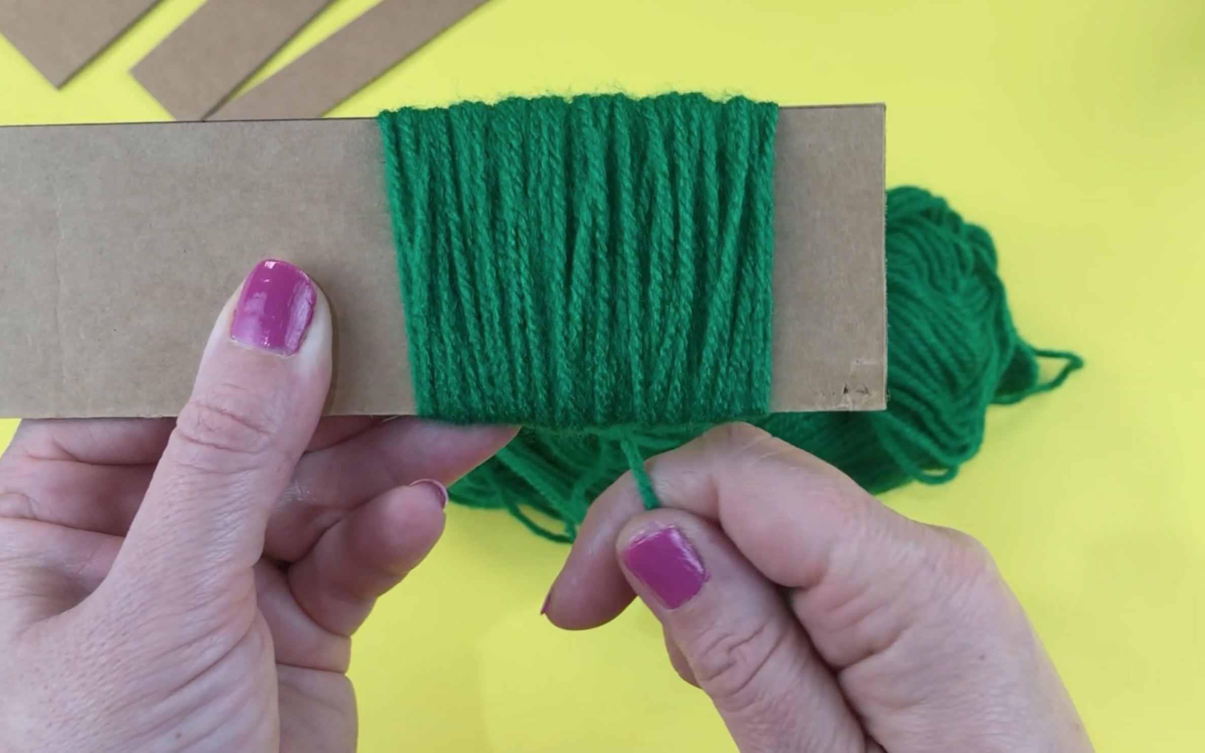 A piece of cardboard with green wool wrapped round it 115 times.