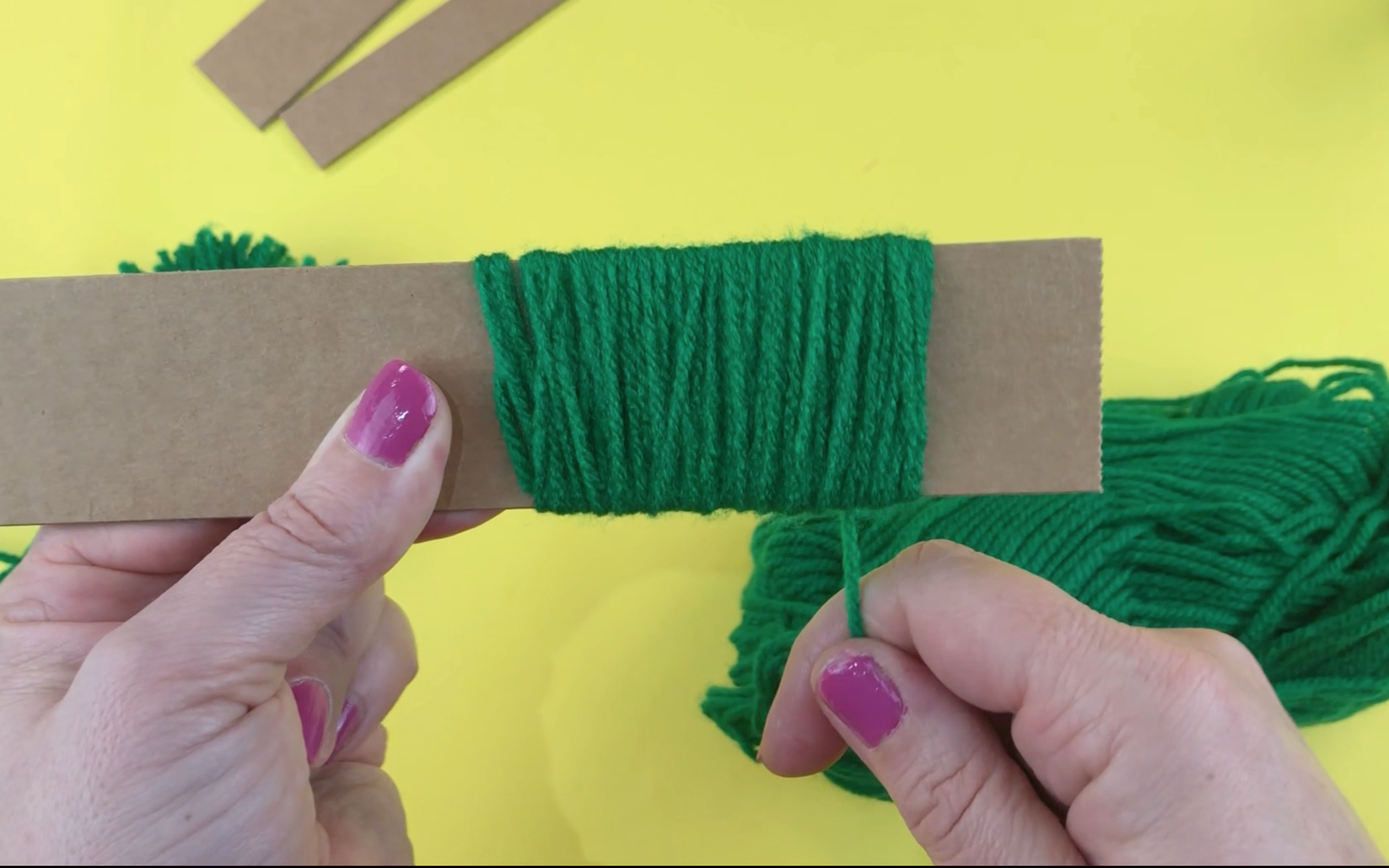 Wrapping green wool around a piece of cardboard 4cm wide