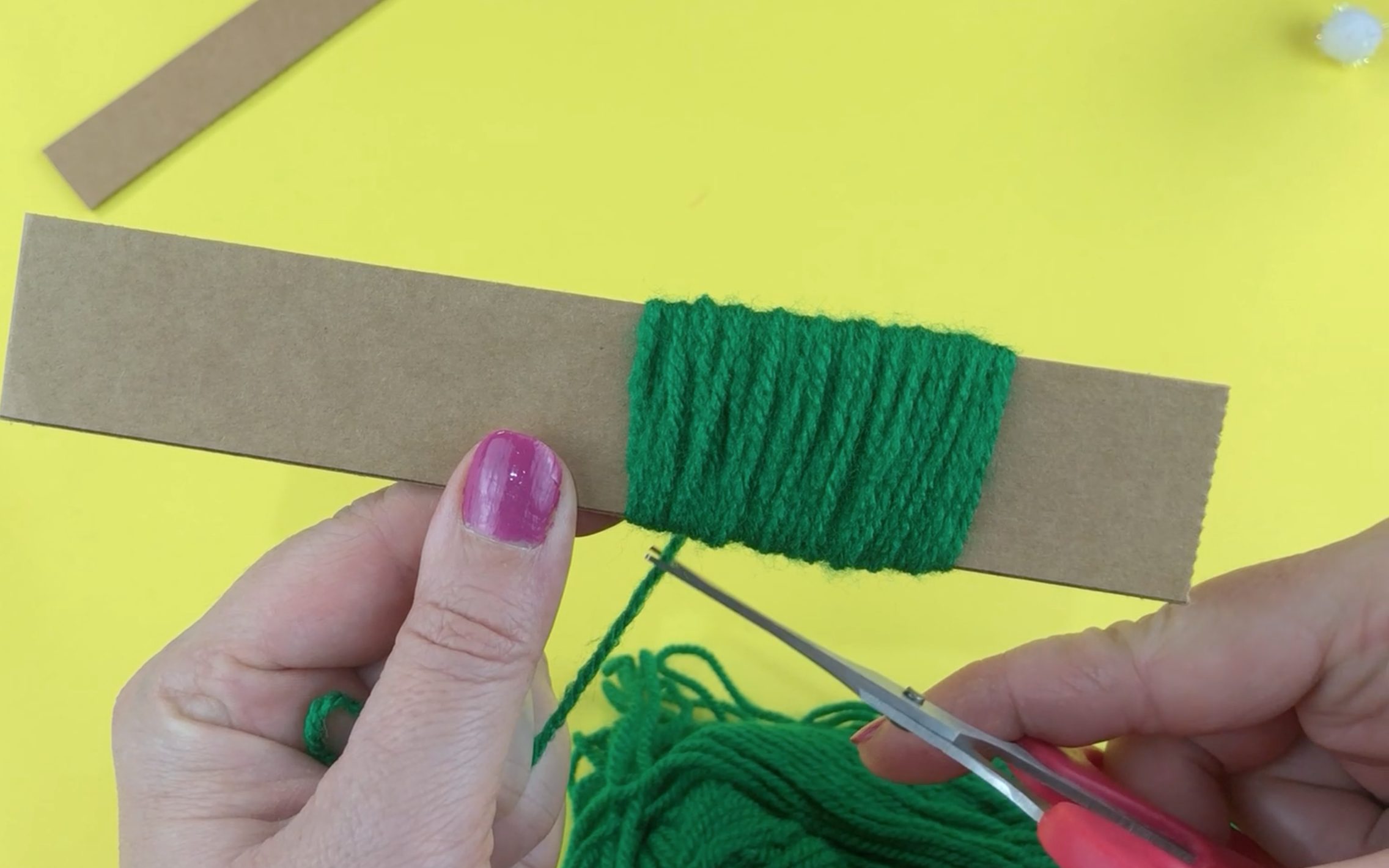 Wrapping green wool around a piece of cardboard 3cm wide