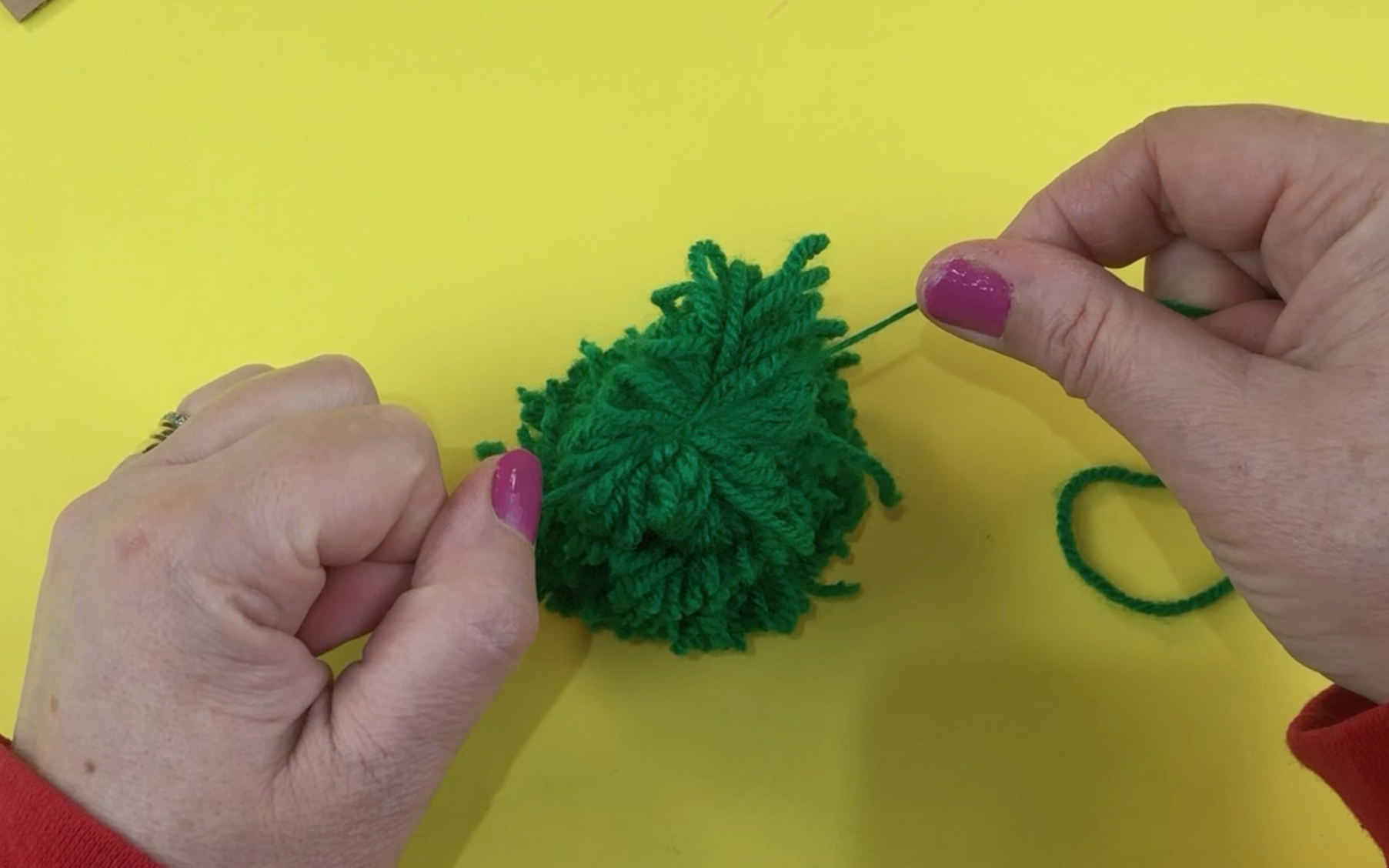 Tying the tied green wool on top of the previously tied green wool