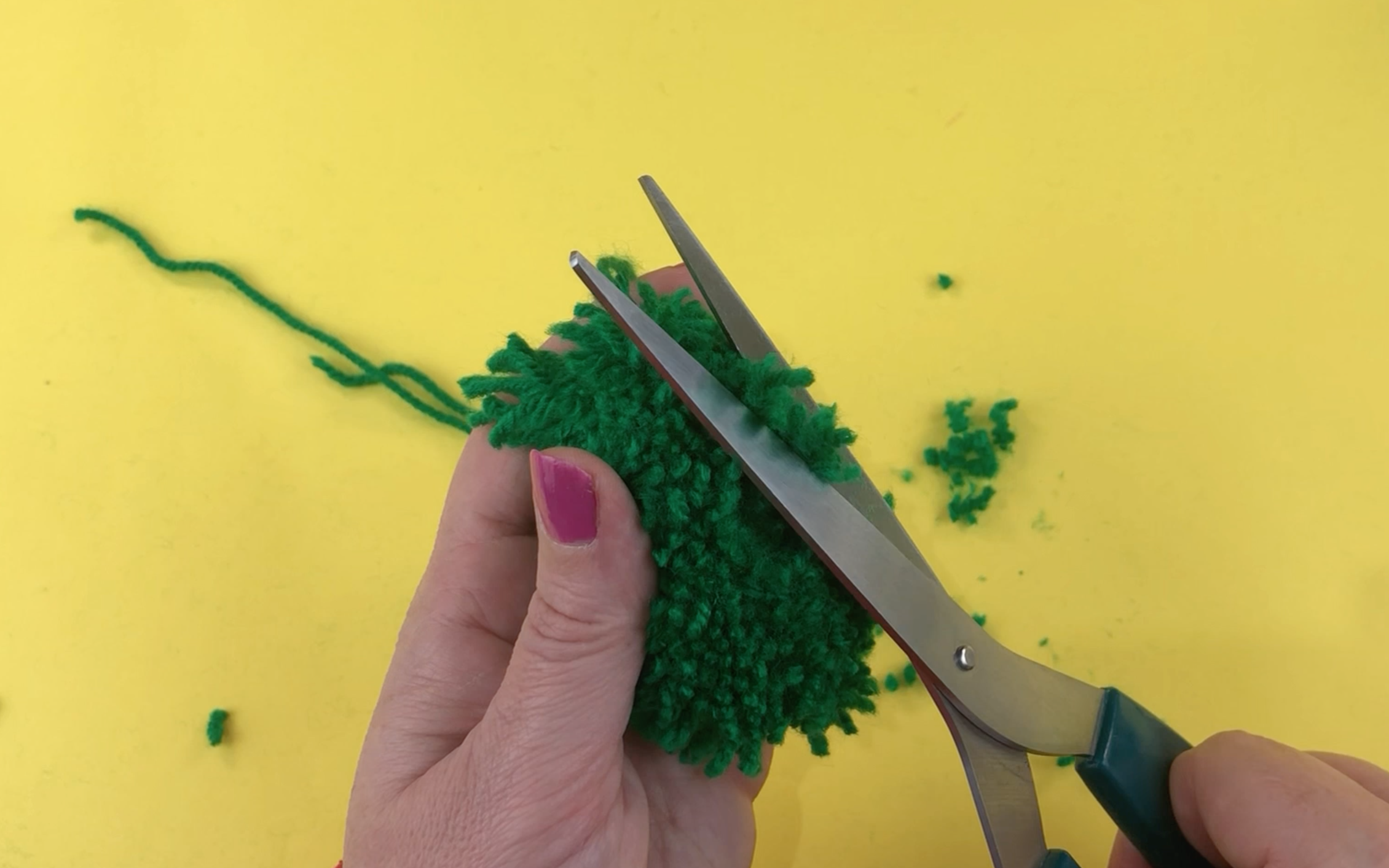 Trimming the edge of the pompom with some large sharp scissors 