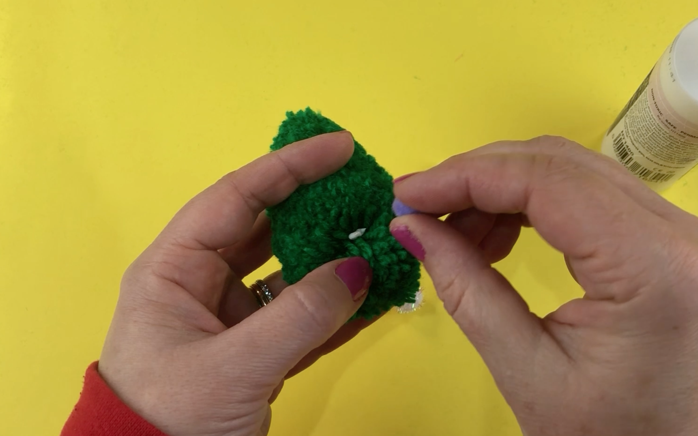 Parting the wool of the pompom christmas tree to add glue and the small colourful pompoms