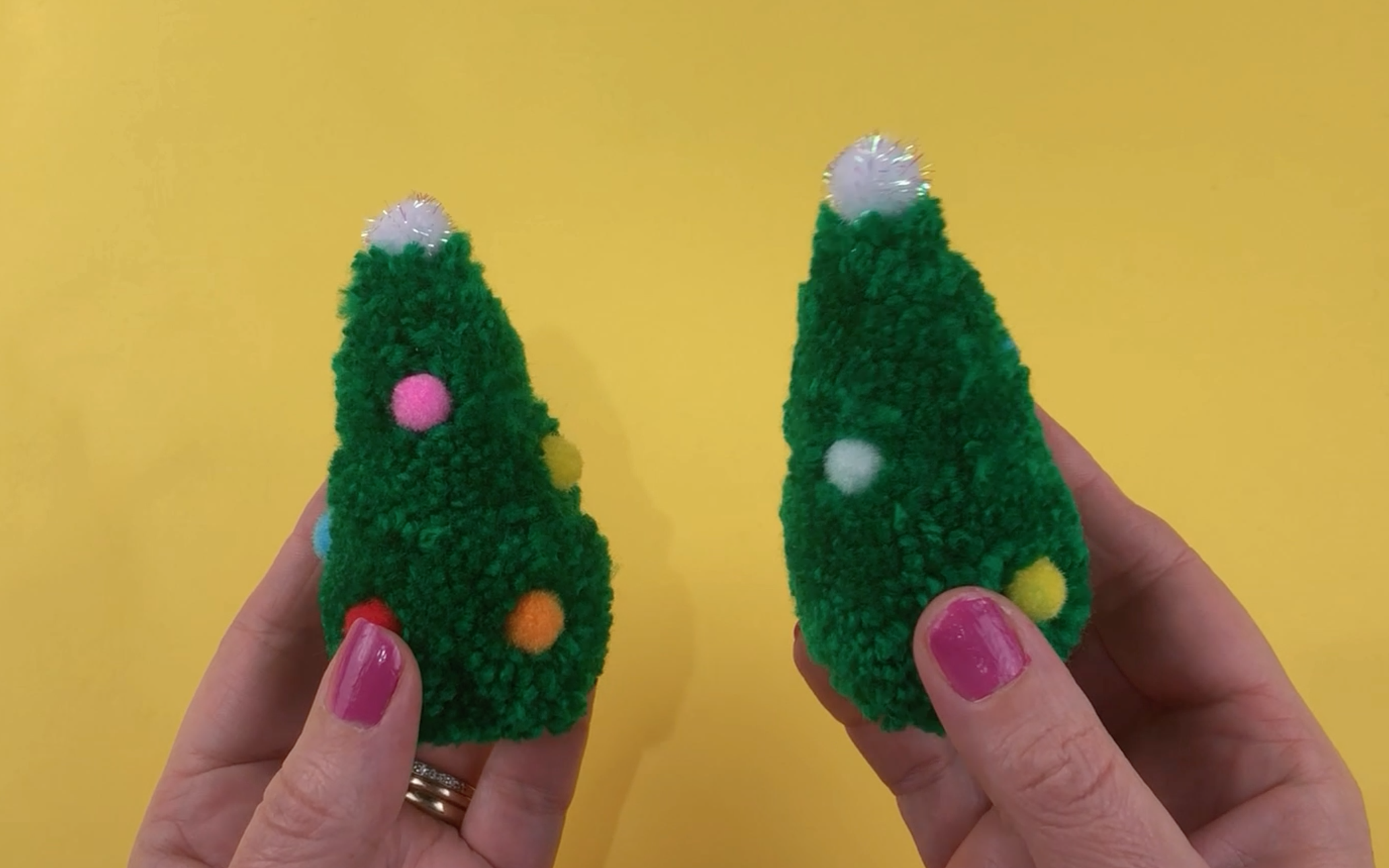 The finished pompom christmas trees with colourful pompoms to look like decorations
