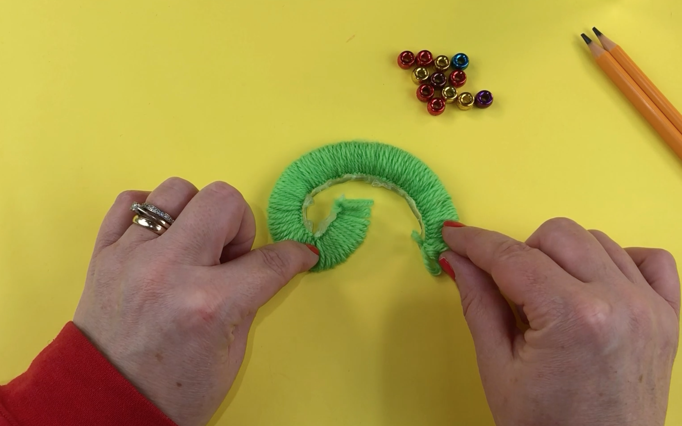 The looped wool removed from the pencil. the wool is a starting to curl round.