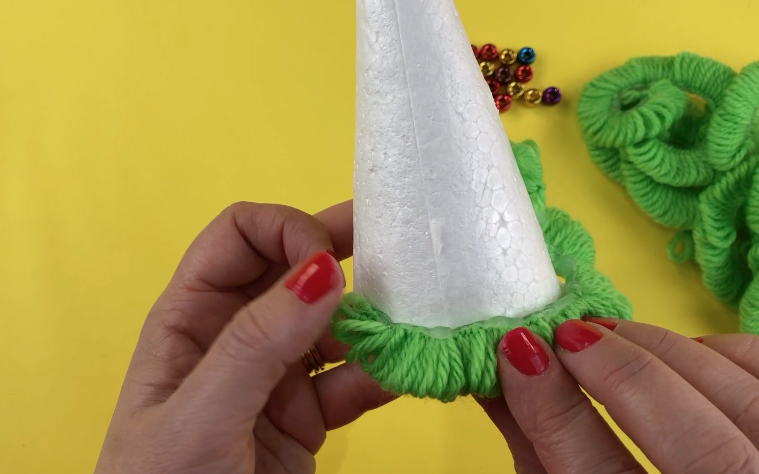 Pressing a strip of the wool curls into the hot glue.