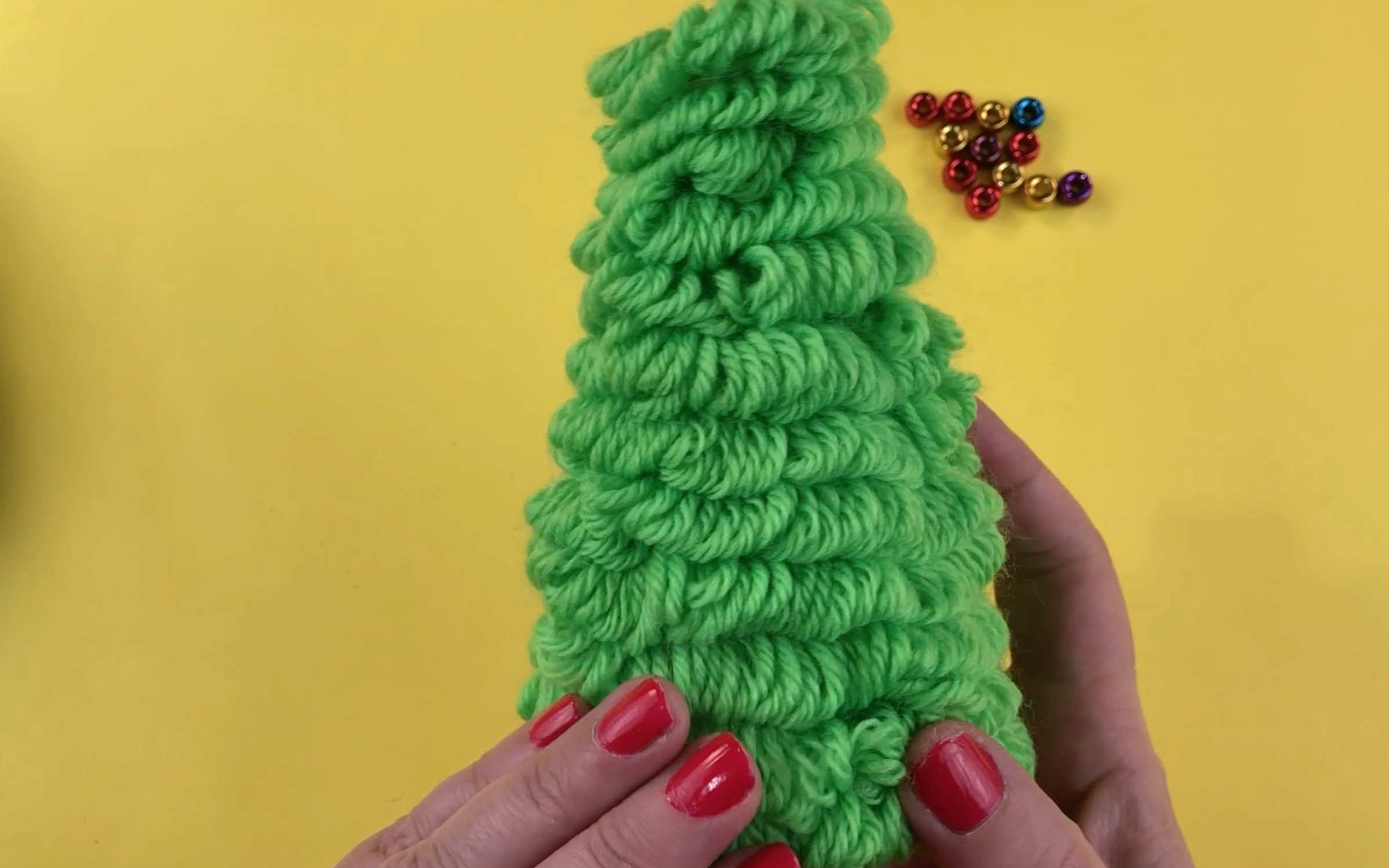 Polystyrene cone covered in  green wool loops