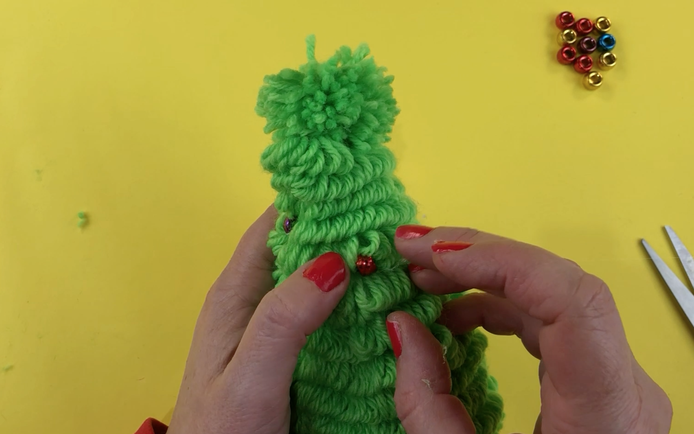 Adding coloured beads to the wool wrapped tree. 