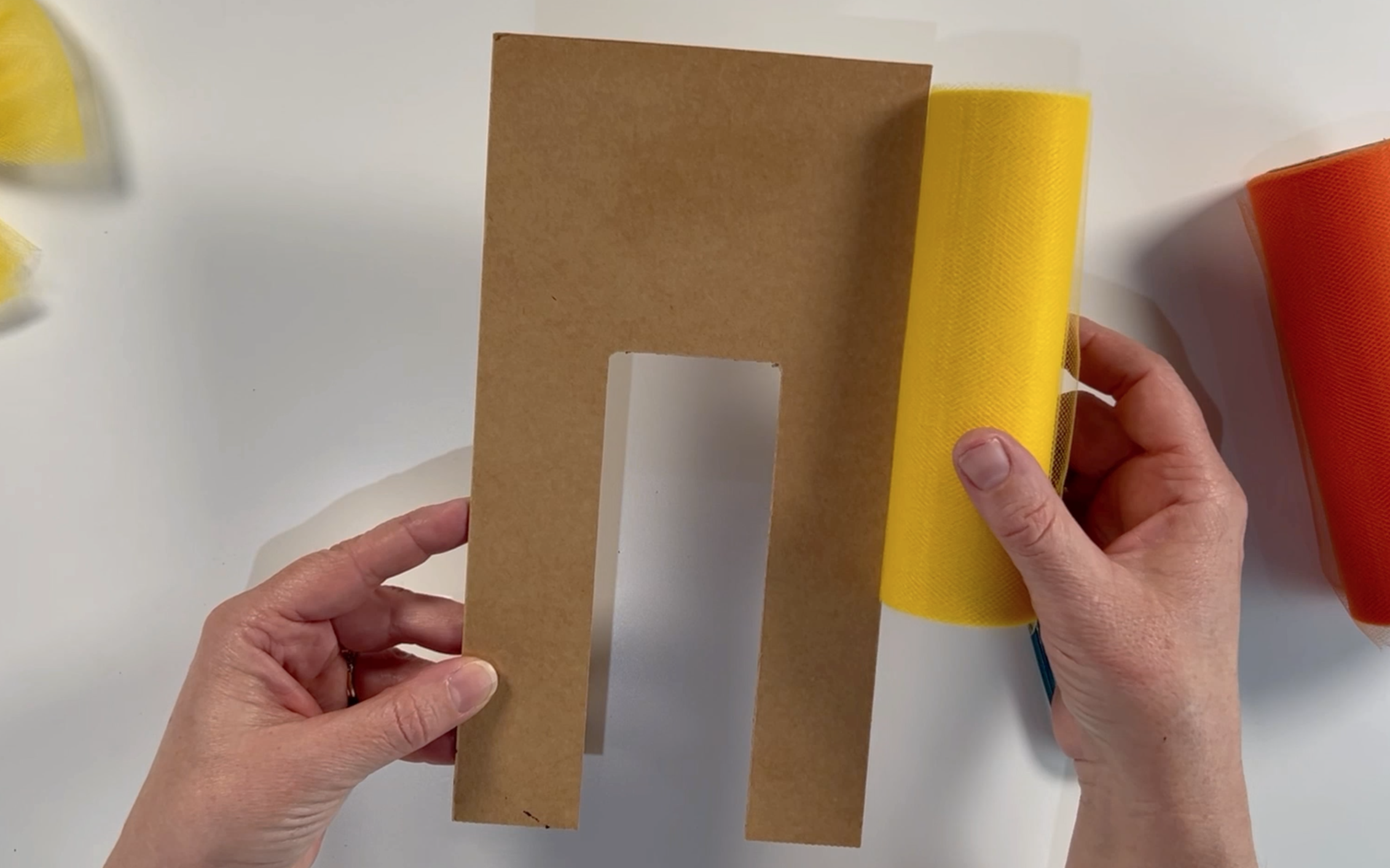 Showing a cardboard template which is 9.5 inches high against a roll of tulle which is 6 inches high.