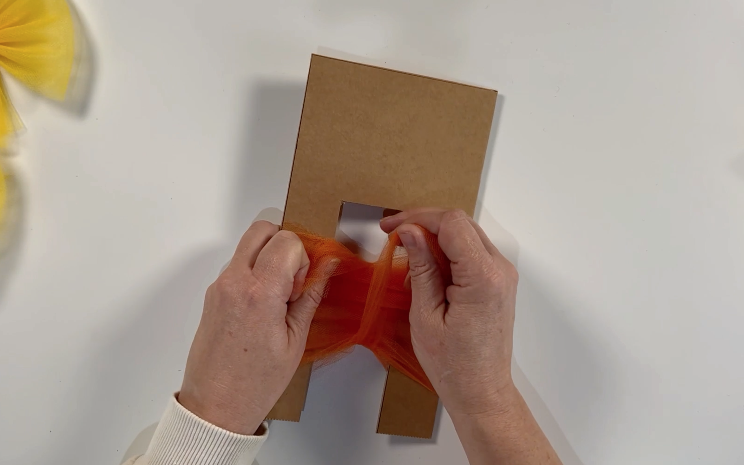 Tying the tulle that has been pulled down to the bottom of the template with another piece of tulle