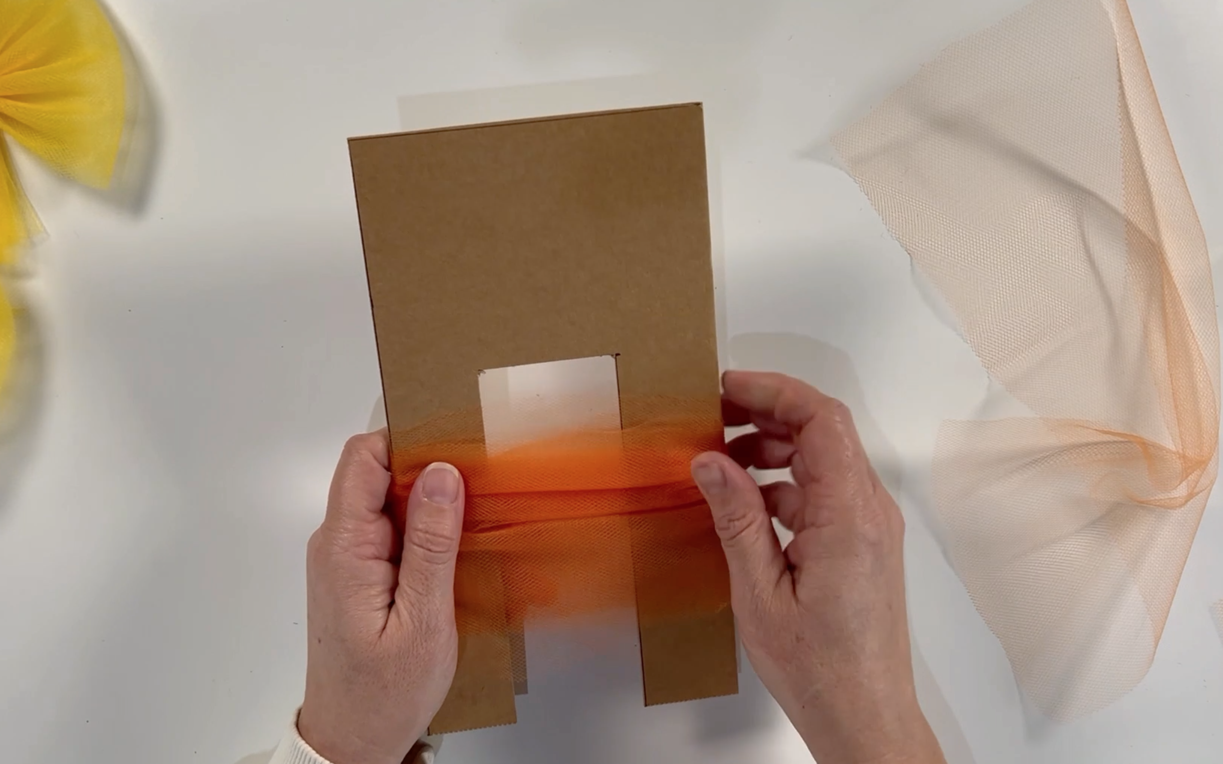 Pulling the wrapped tulle down to the bottom of the cardboard template