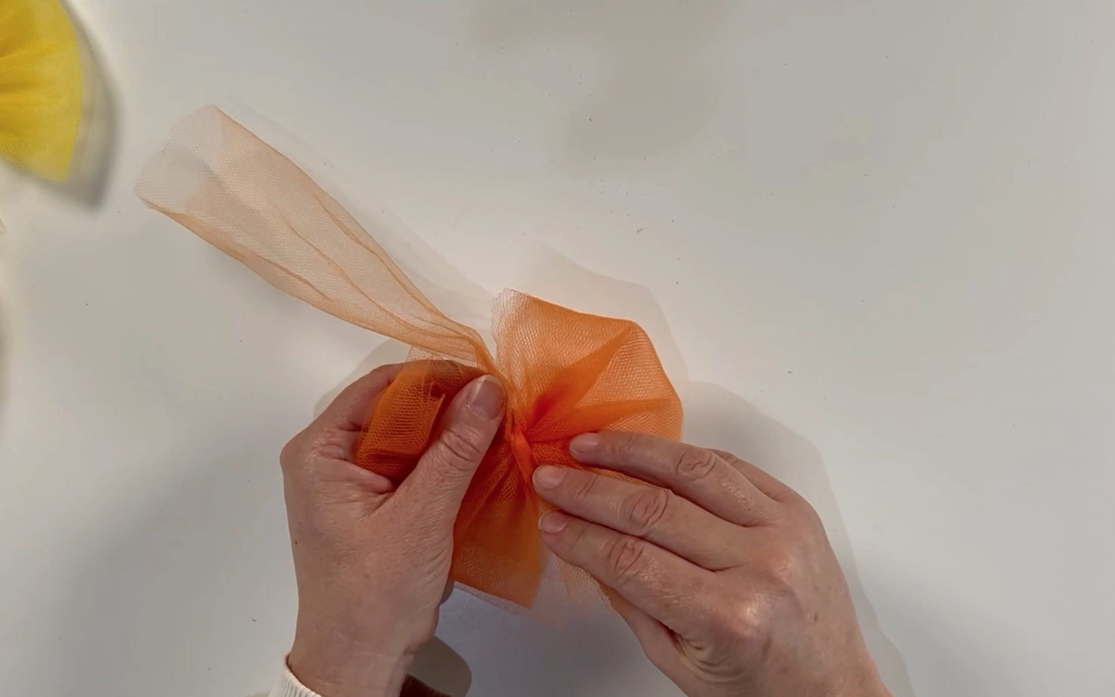 Wrapping the tulle around the centre of the bow to hide the knots and finish the bow off.