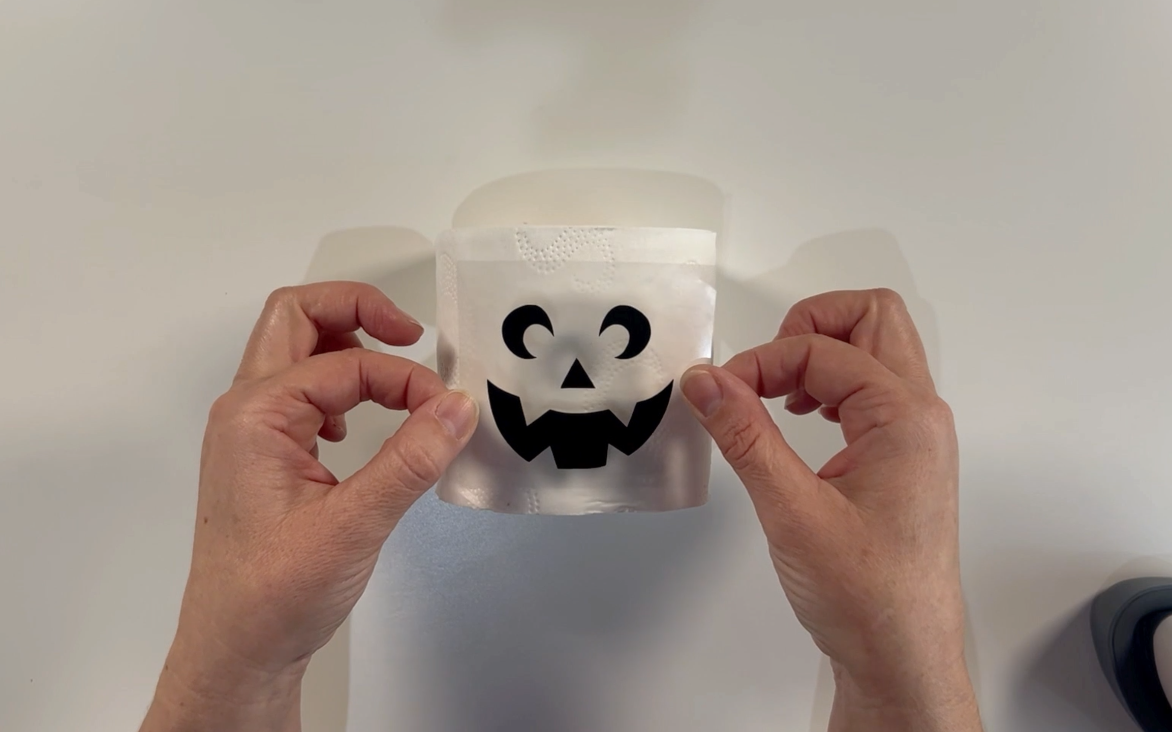 Positioning the vinyl ghost face on the front of the toilet roll 