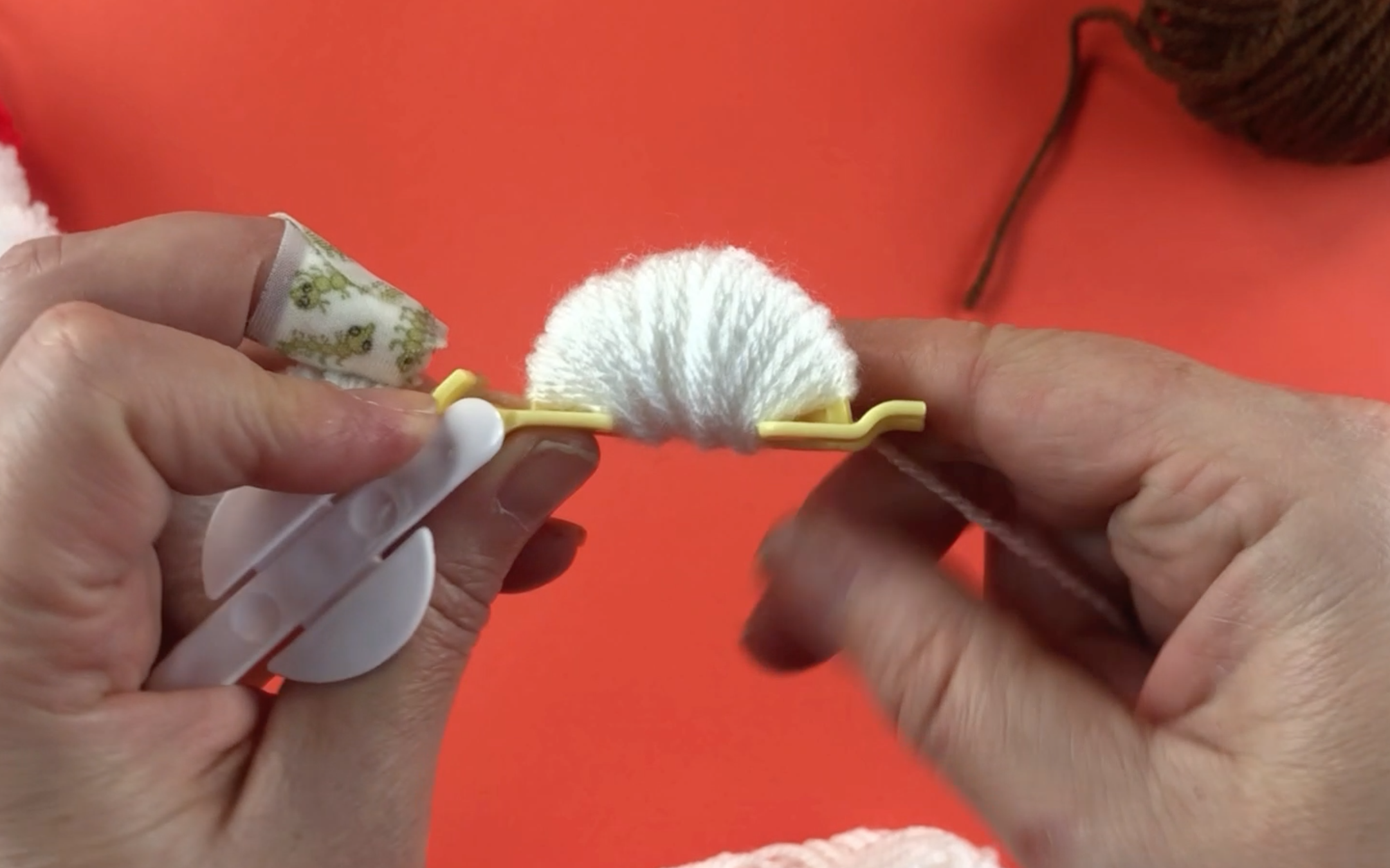 Wrapping white wool around a pompom maker to make a pompom