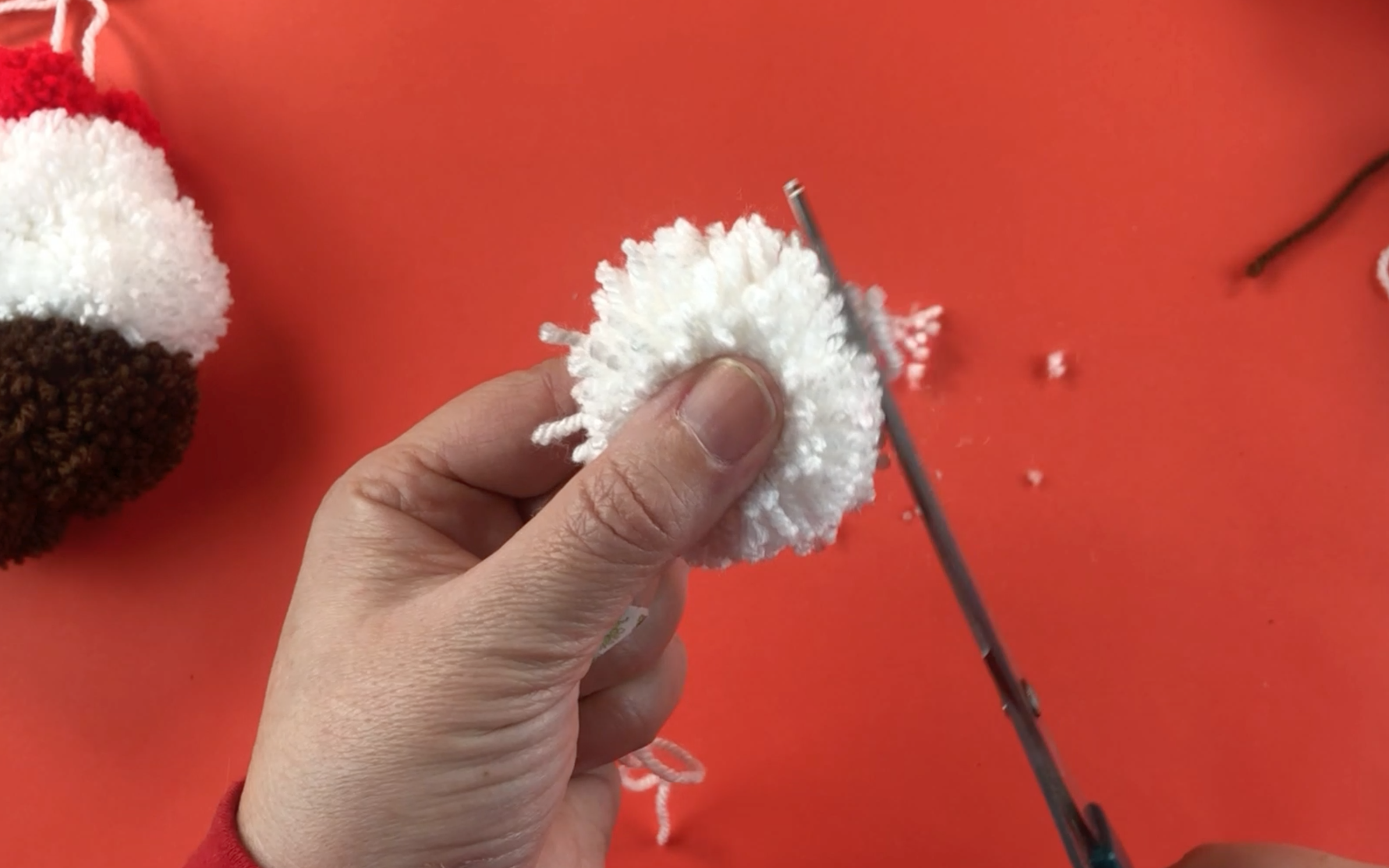 Trimming the edge of a white pompom to make it neat.
