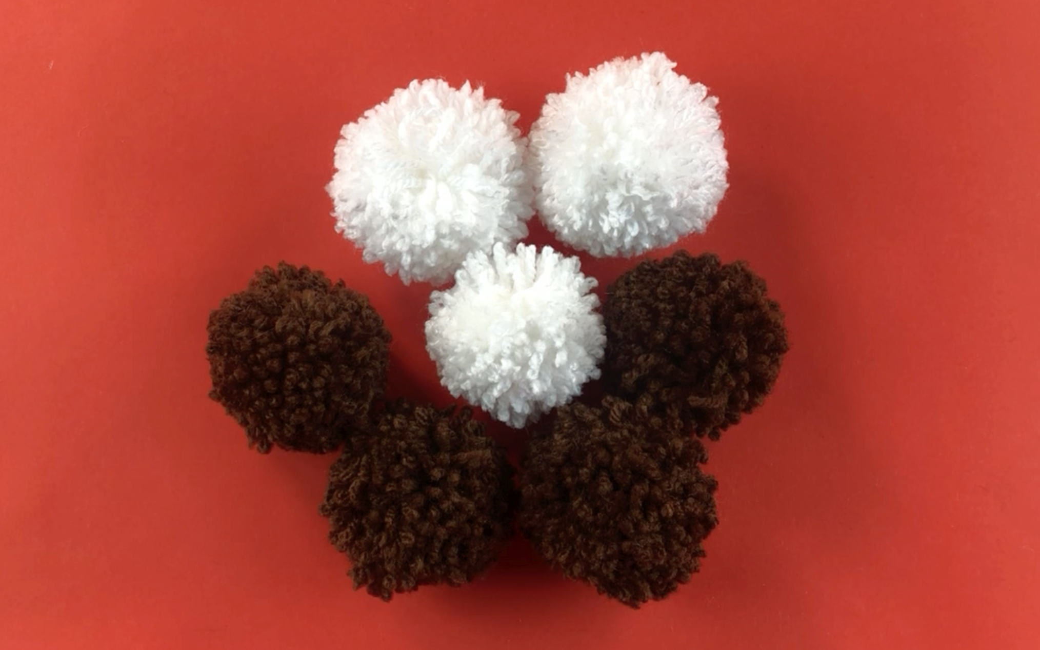 3 small white pompoms and 4 small brown pompoms