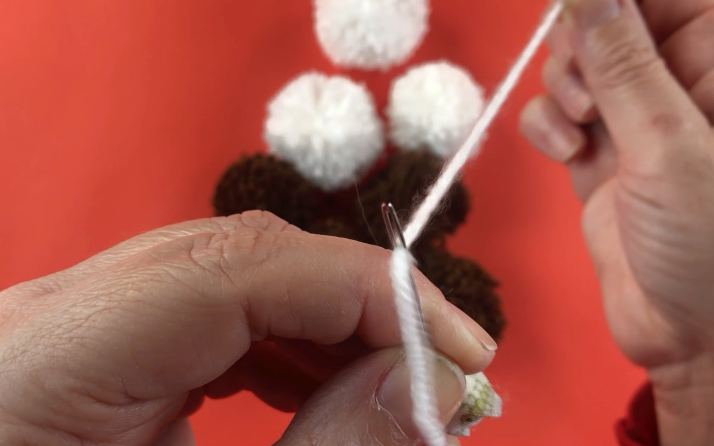 Threading white wool through a large eye needle