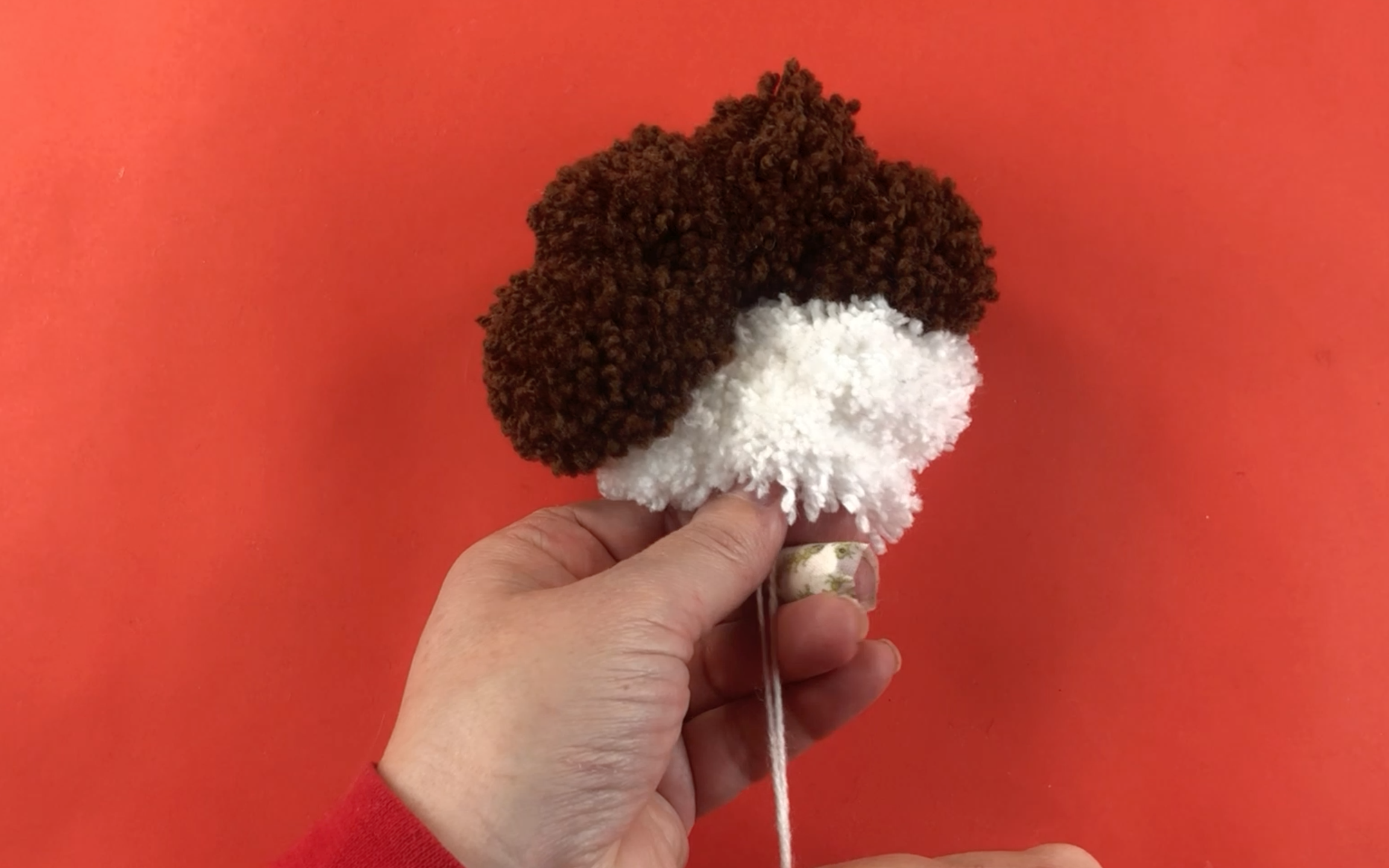 Pulling the wool tight to hold all the pompoms together