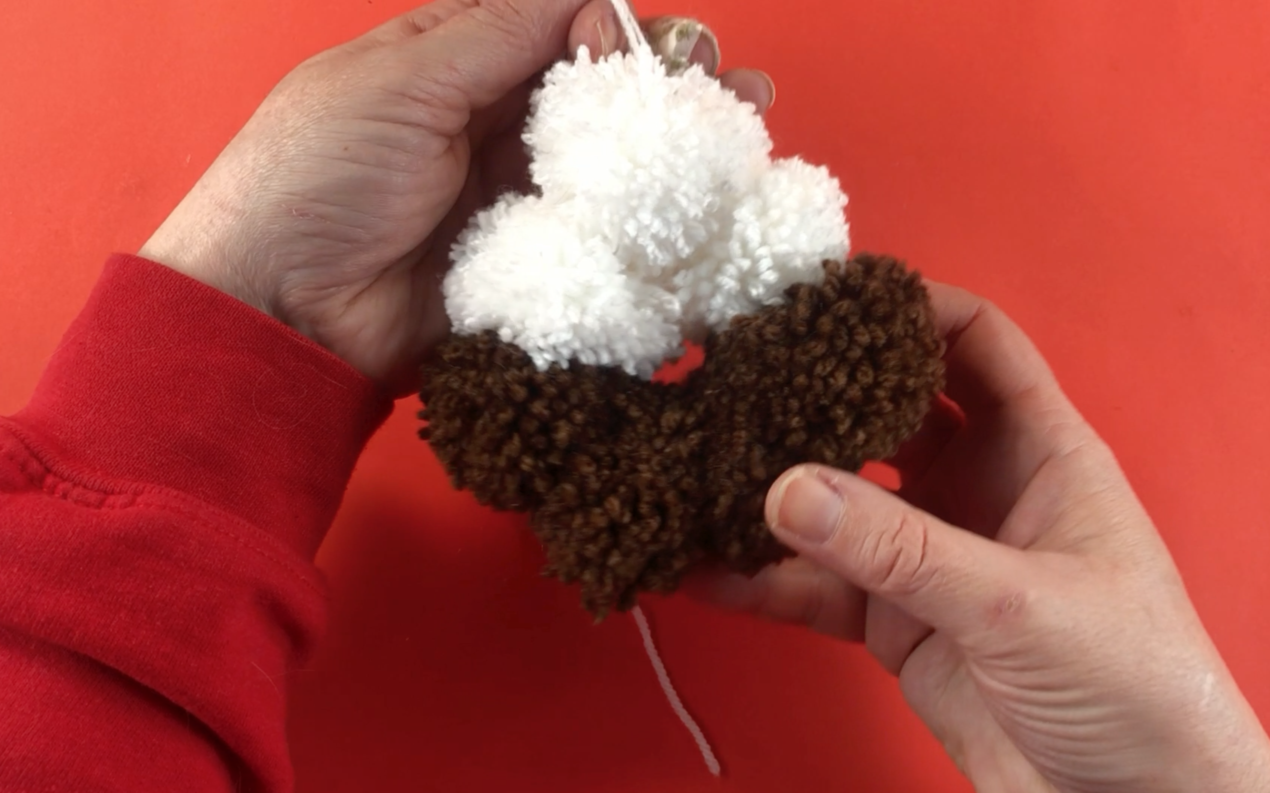 The brown and white pompoms all tied together. They are now all in a circle and starting to look like a Christmas pudding