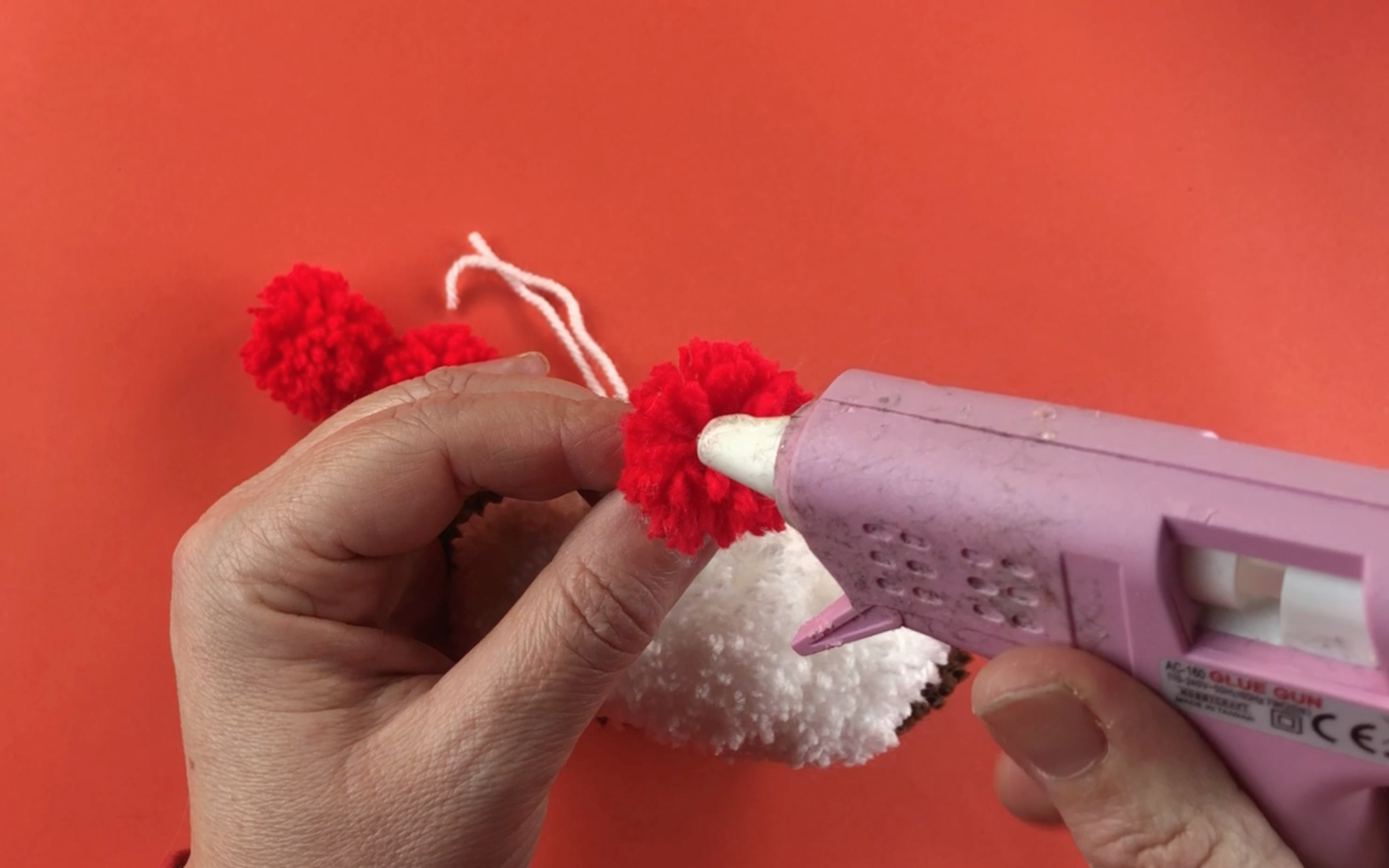 Adding hot glue to a red pompom