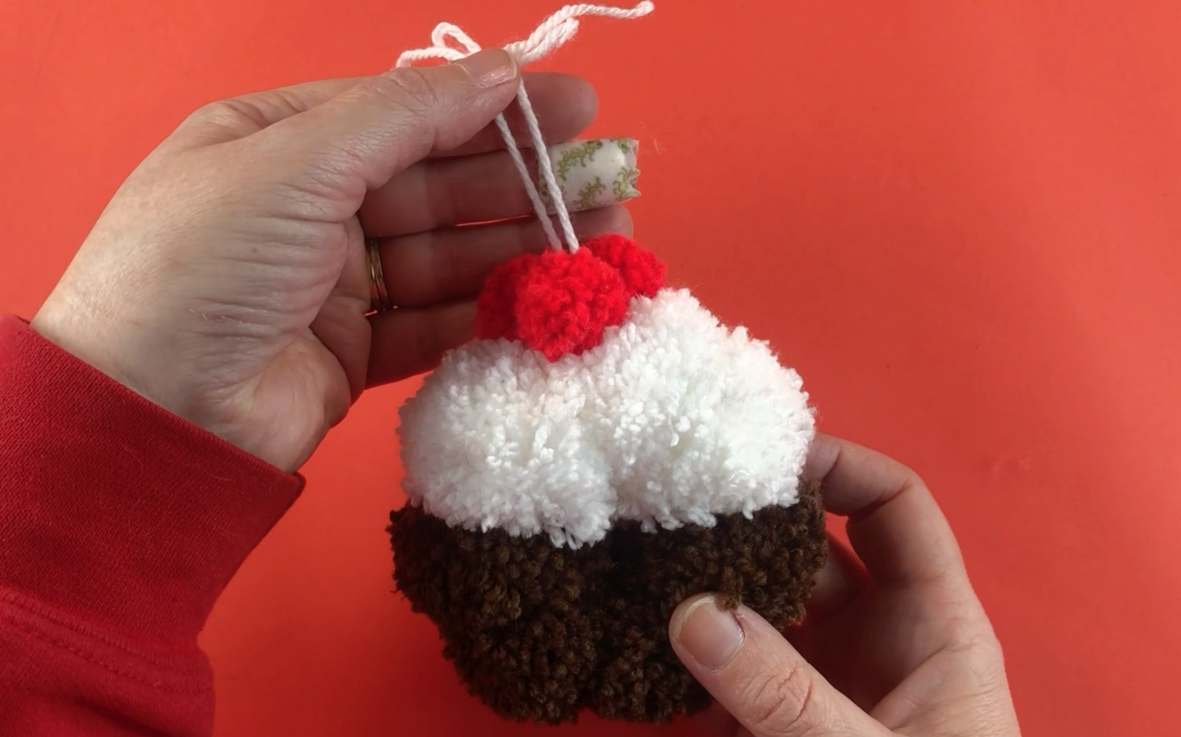A completed pompom christmas pudding using red, white and brown pompoms.