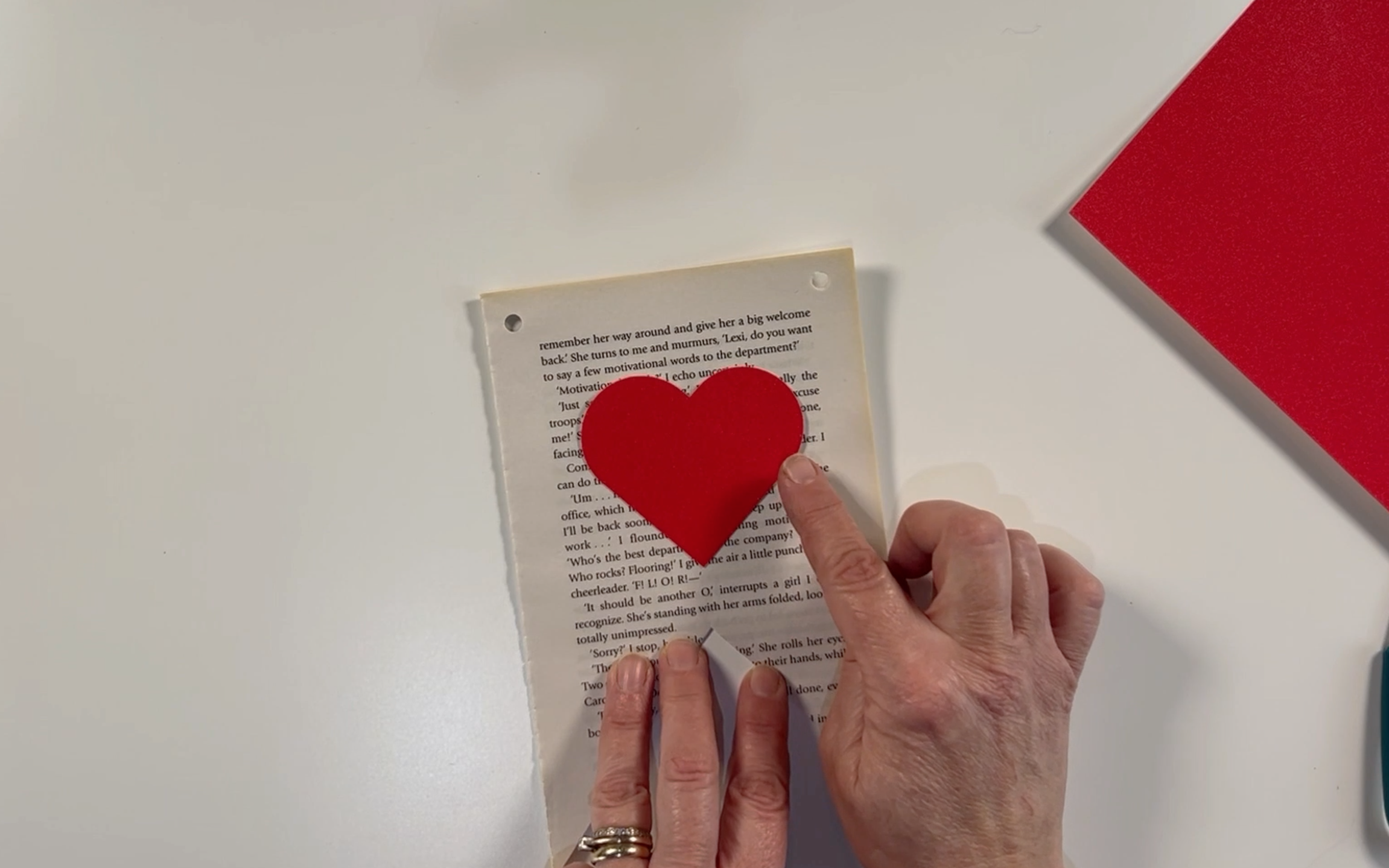 Placing the cut red hearts on the front of the book page to check it is the right size