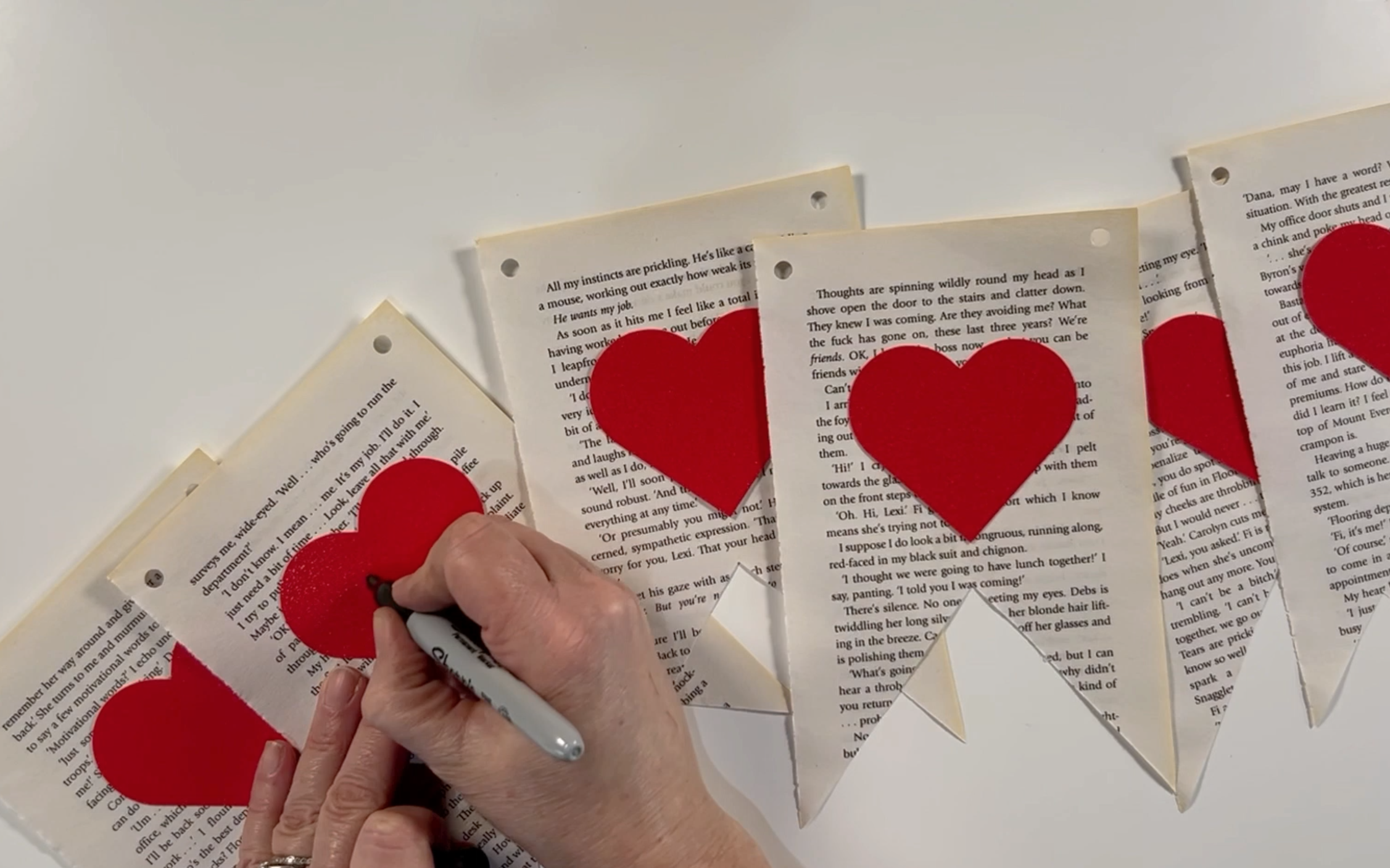 Writing the word love in black sharpie on the hearts.