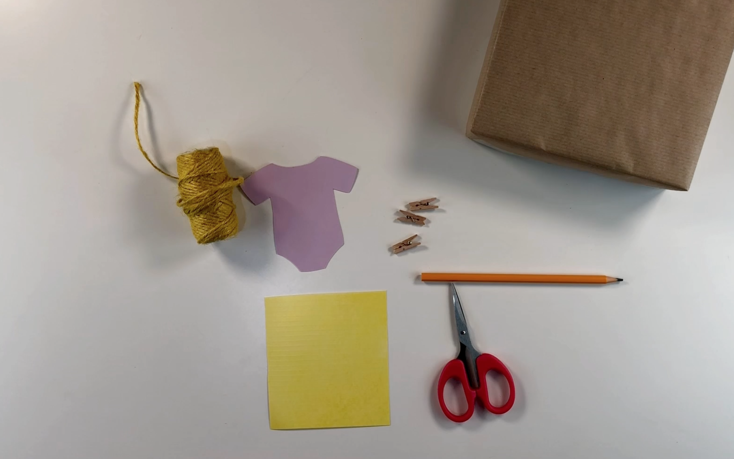 Supplies i need to make baby shower gift wrap: twine, card, wooden pegs, scissors, and baby vest gift tag.