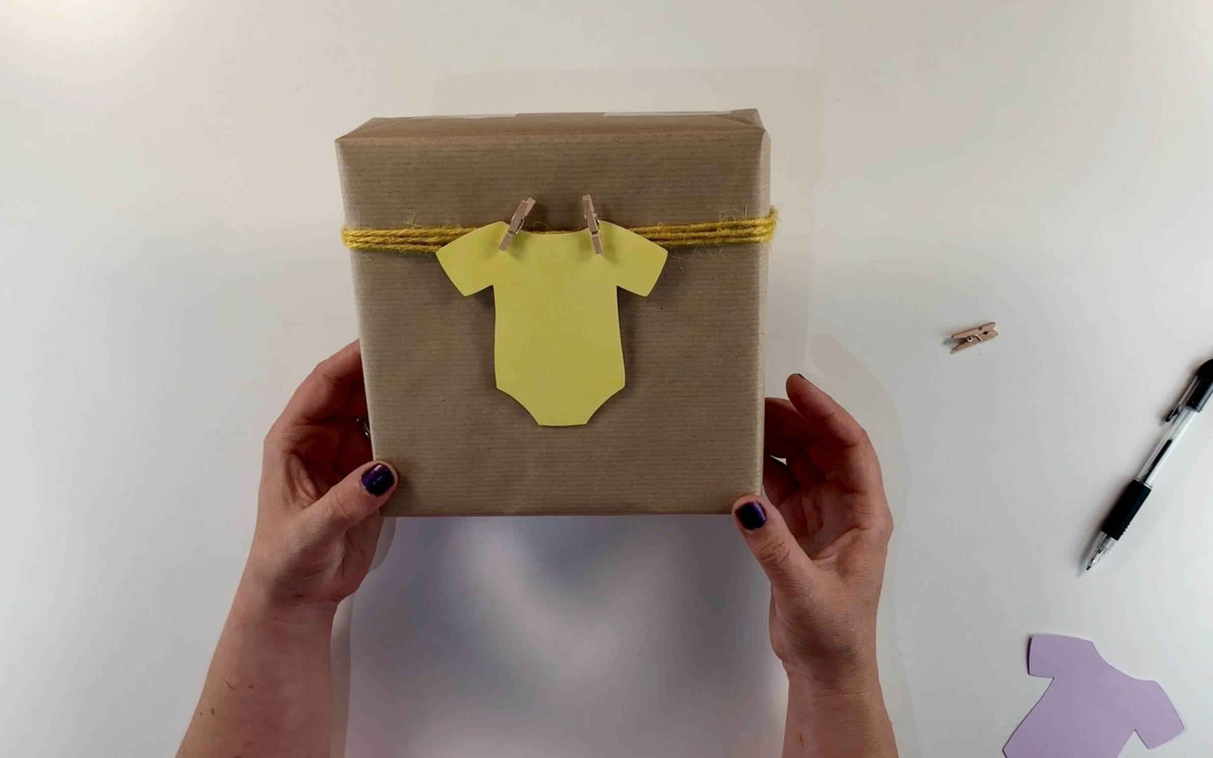 Pegging the baby vest tag on the twine using the wooden pegs