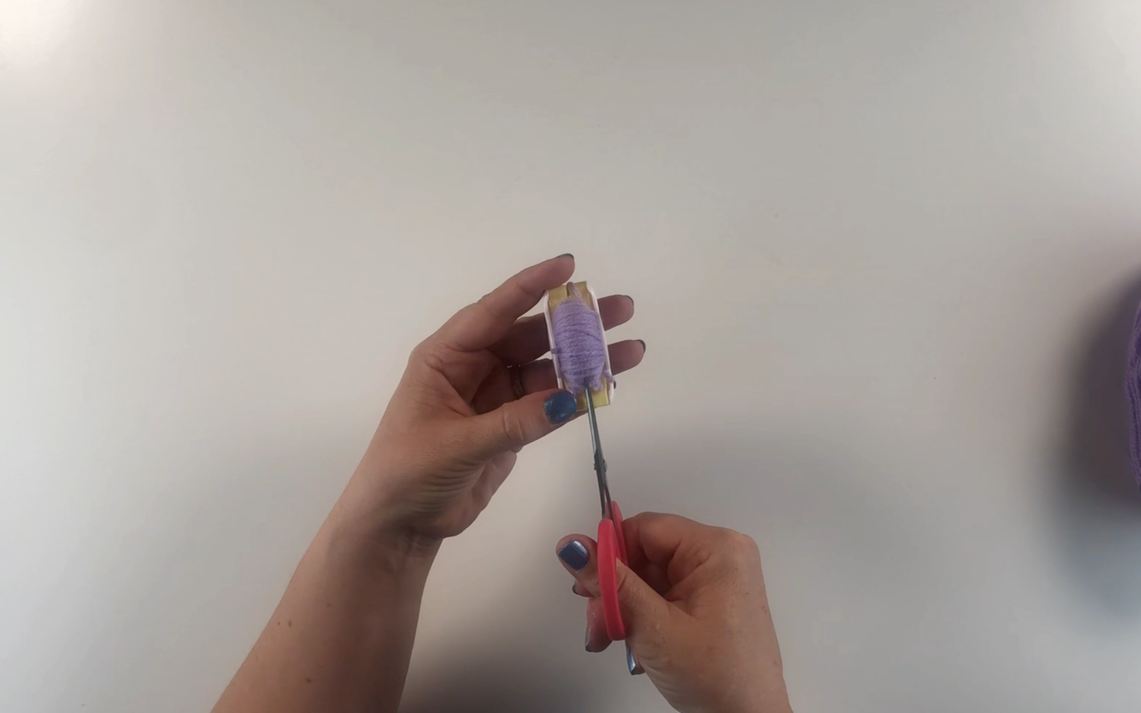Cutting around the pompom maker to cut the wool.