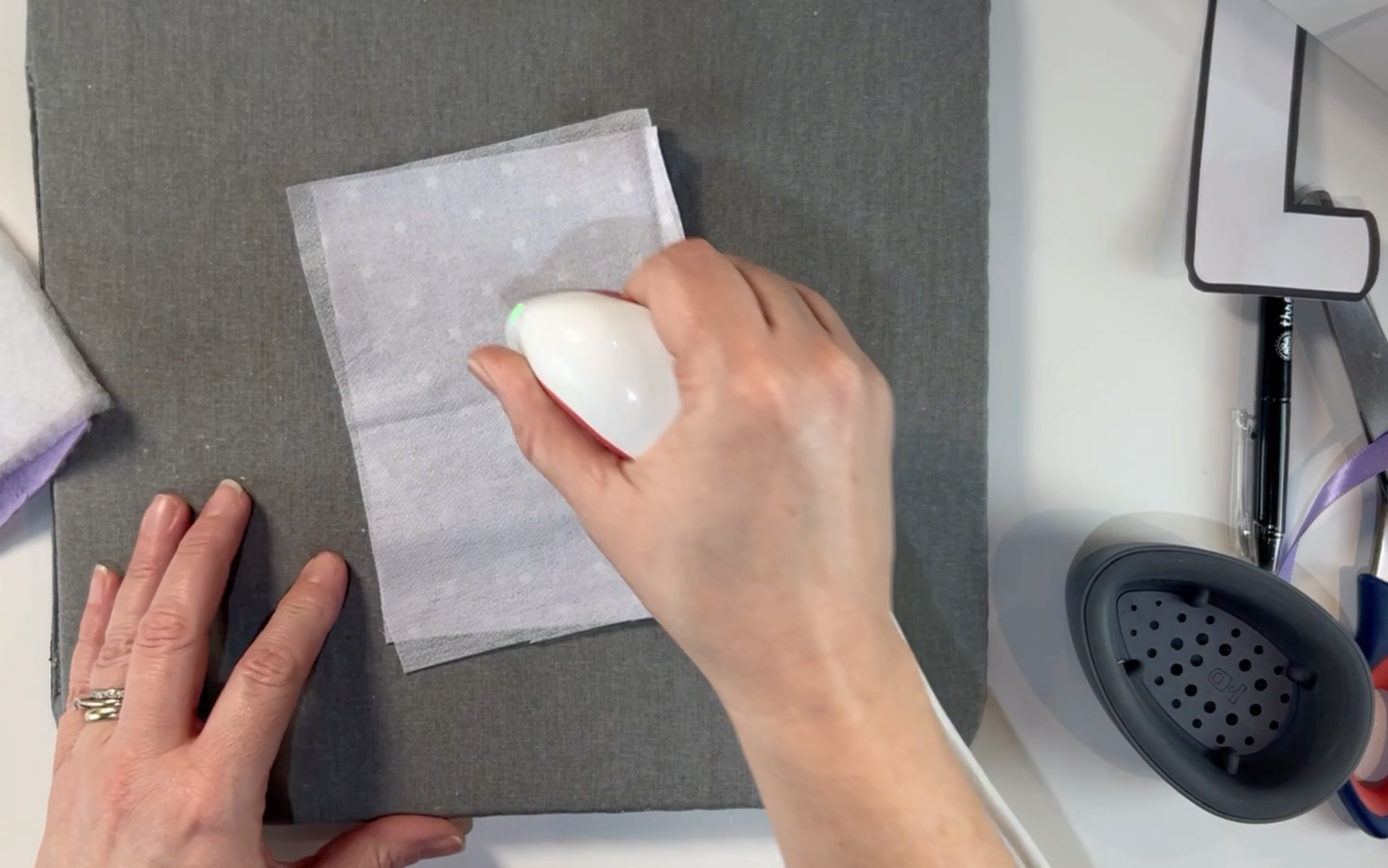 Using the heat press mini to heat the fusible interfacing to the material