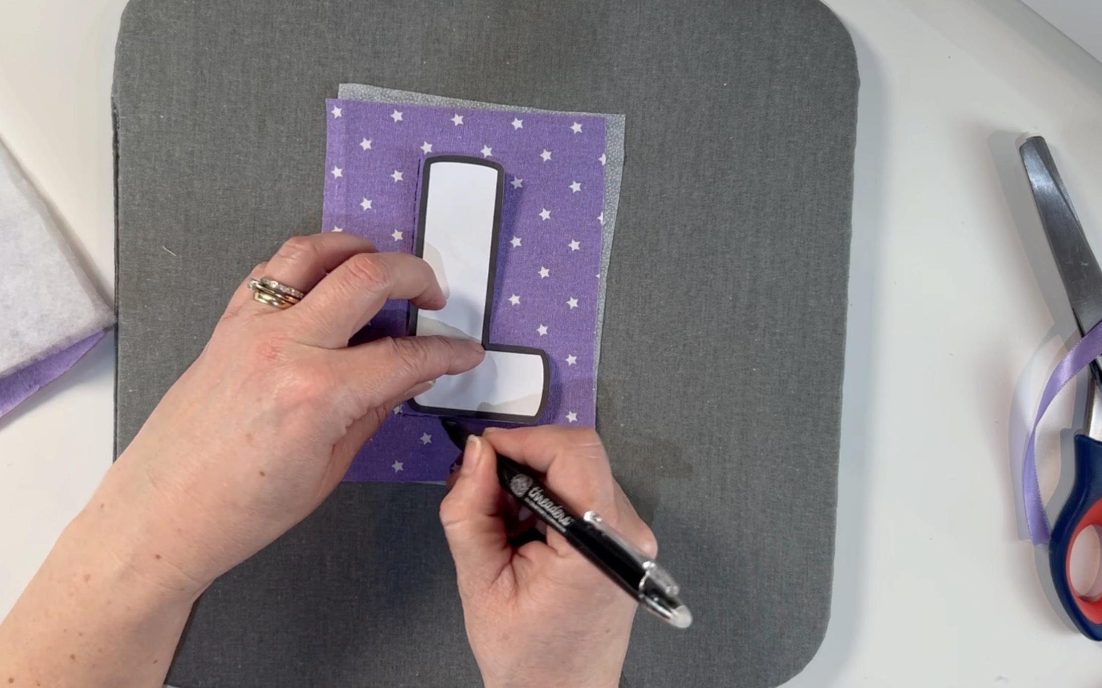 Drawing around the letter template onto the material using a material pen