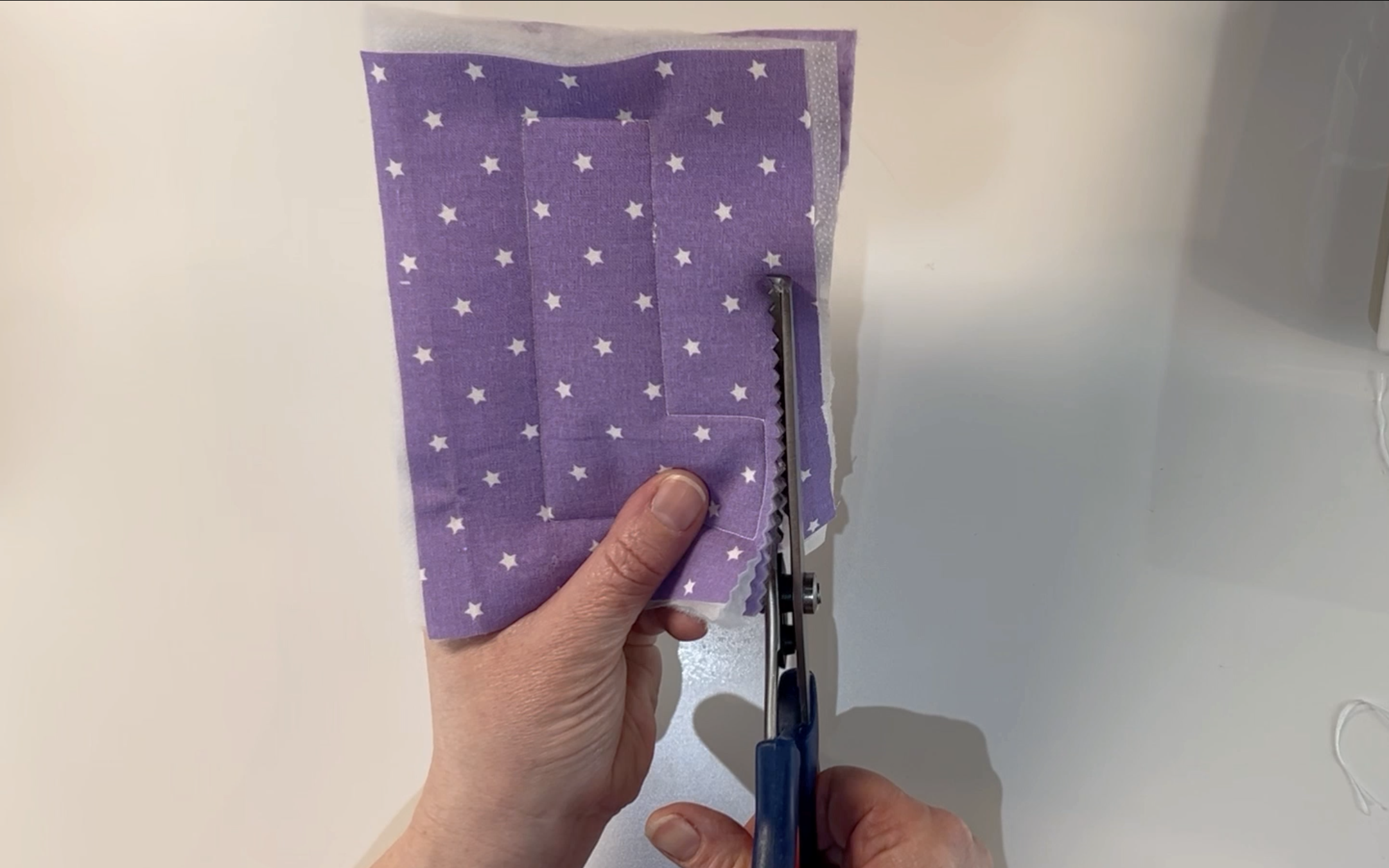 Cutting around the sewn letter with a pair of pinking shears