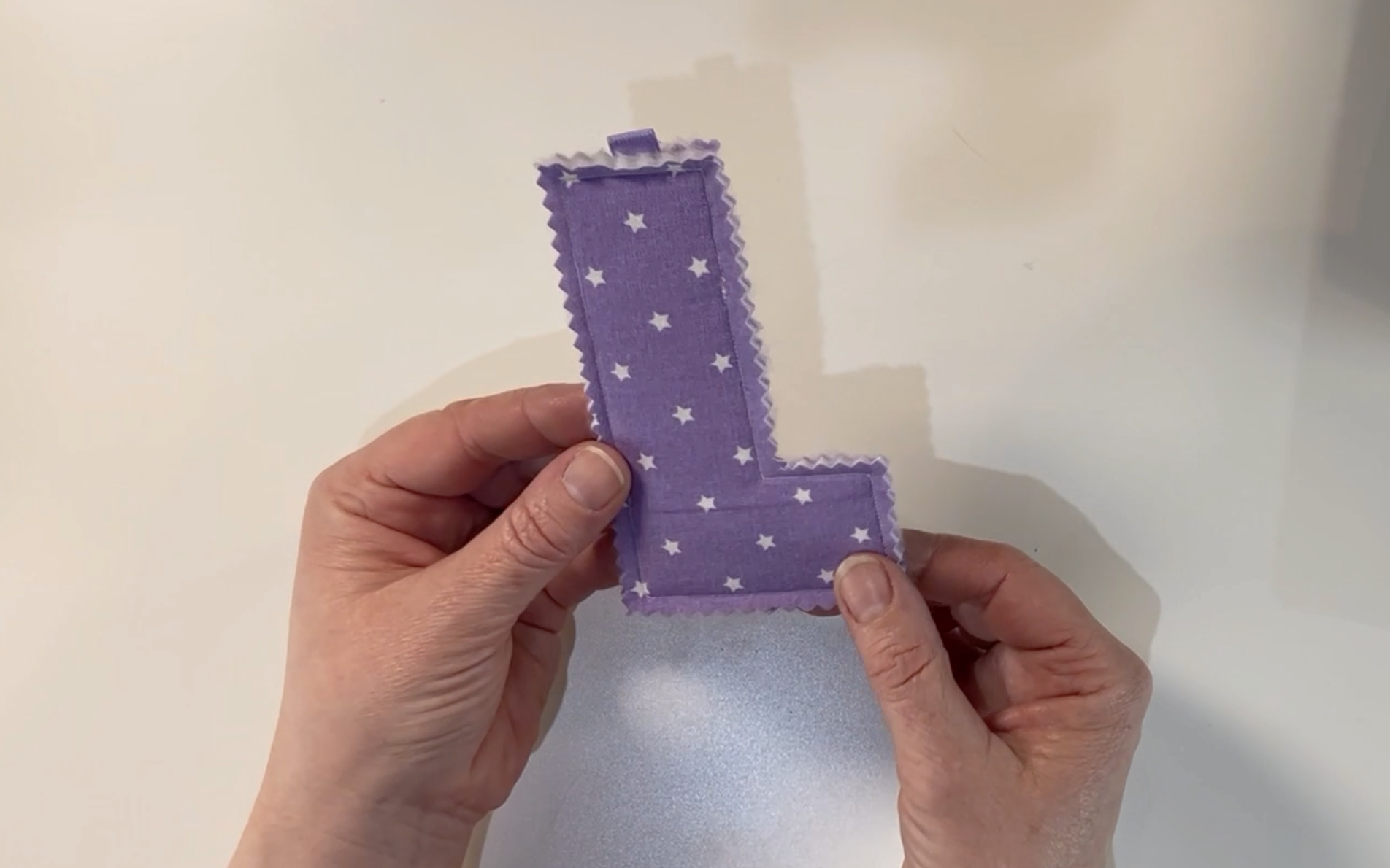 The finished sewn padded letter in purple material with stars on.