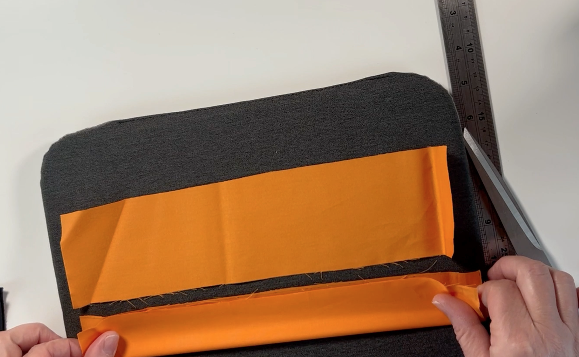 orange material on a pressing mat. One of the pieces of material is folded in half