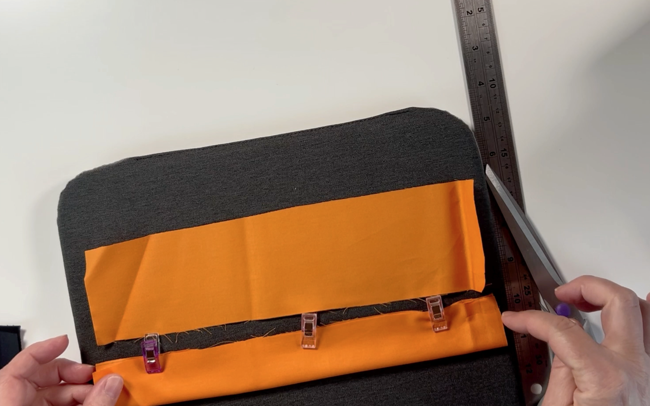 Orange material on the pressing mat. One piece is folded in half and clipped using material clips.