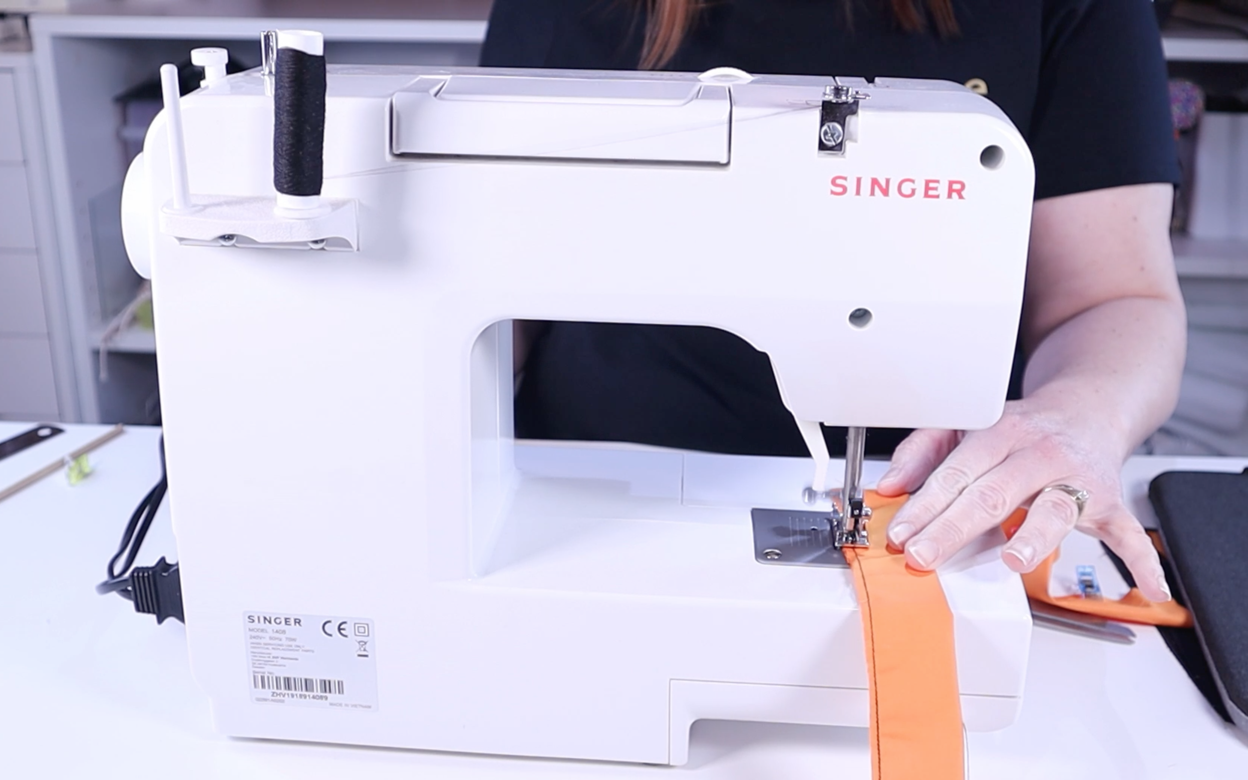 sewing the folded orange material using the singer promise sewing machine
