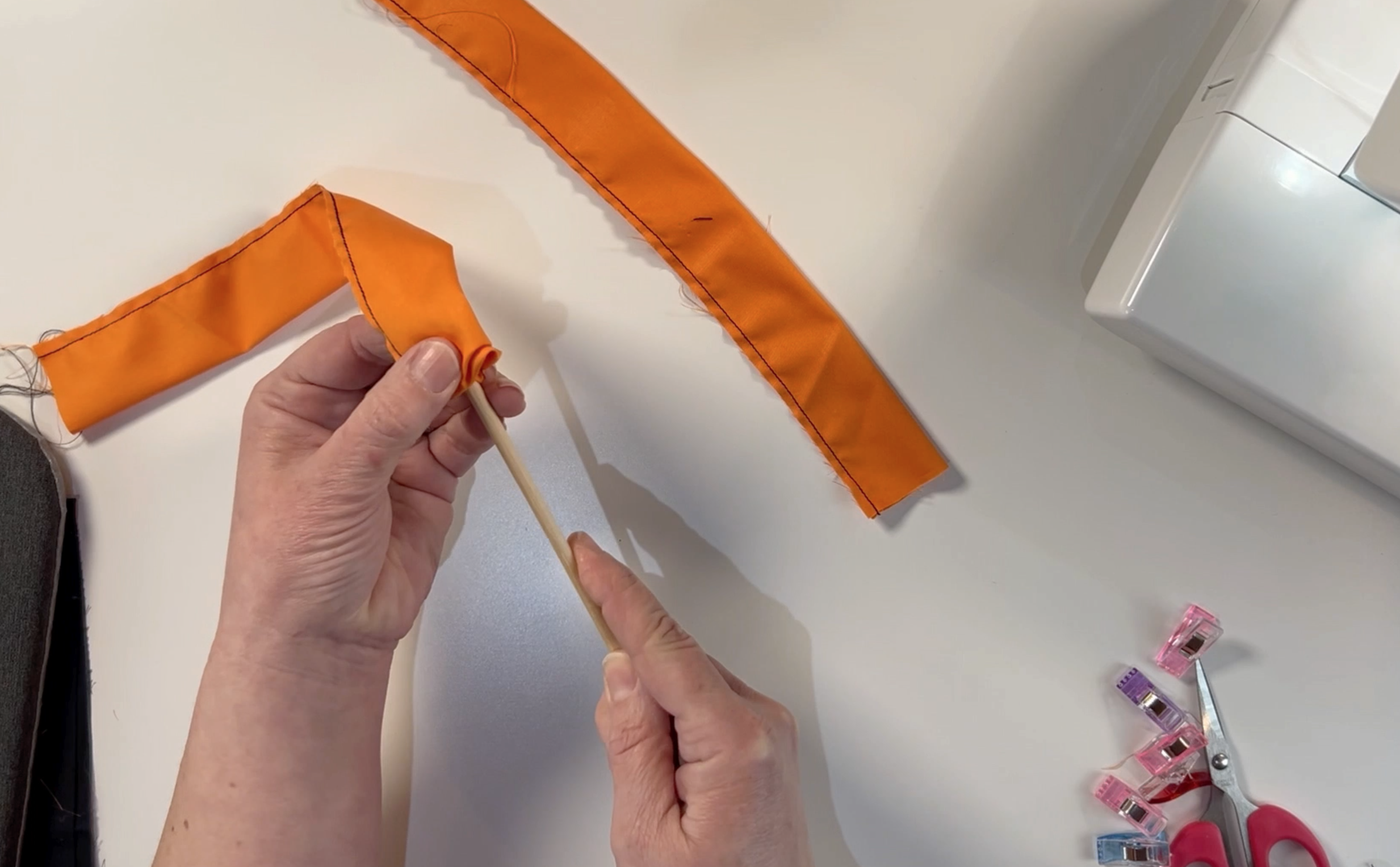 Turning the sewn orange material the right way around using a wooden dowel 