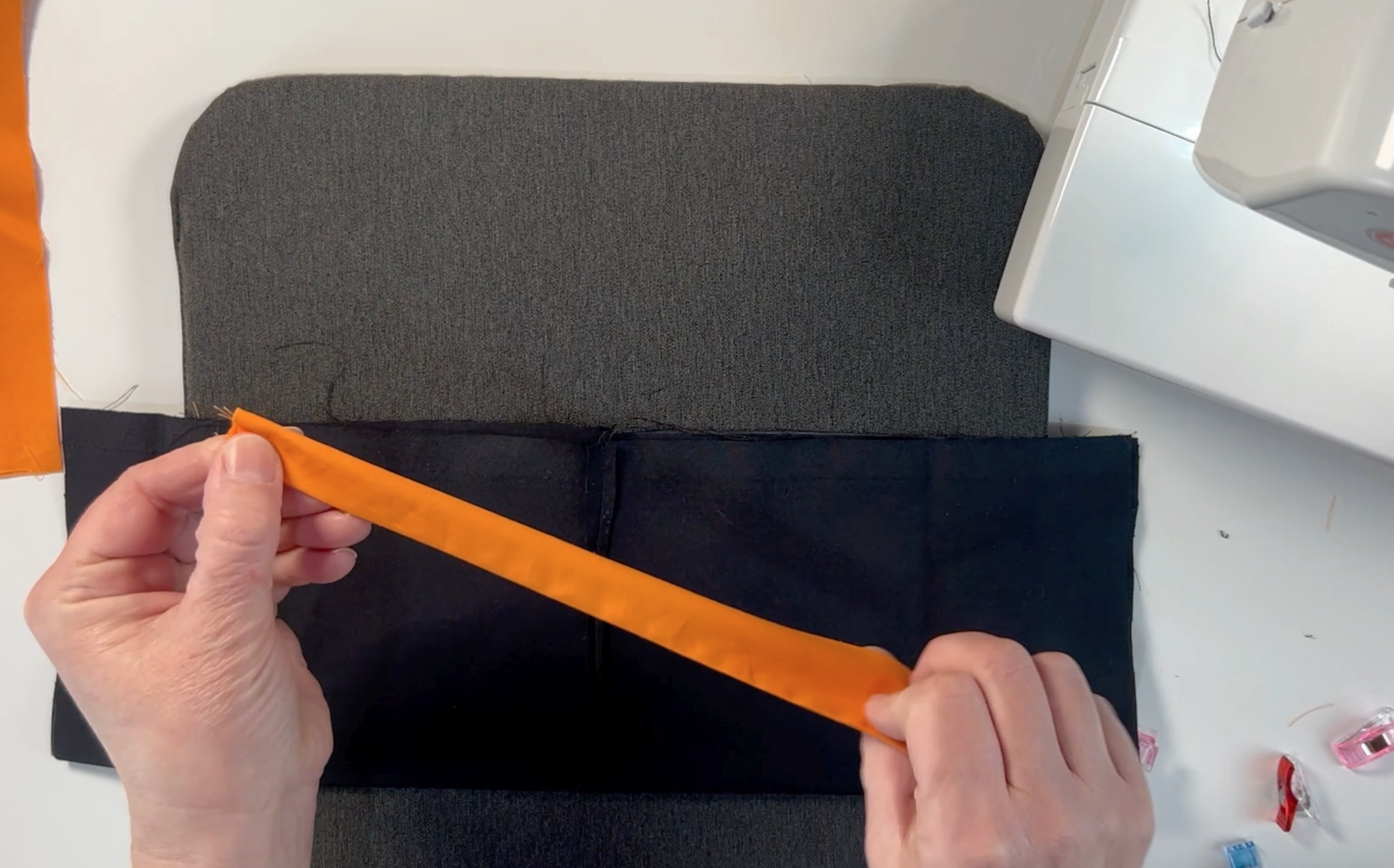 The black material folded in half and the orange straps folded in half to find the centre points
