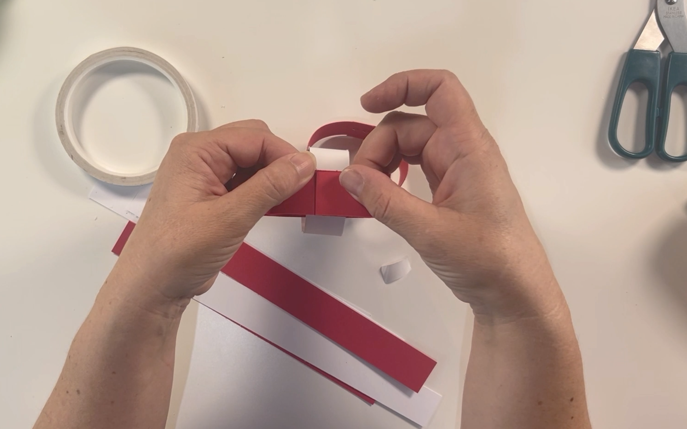 Pressing the card together firmly so the ends stick together.