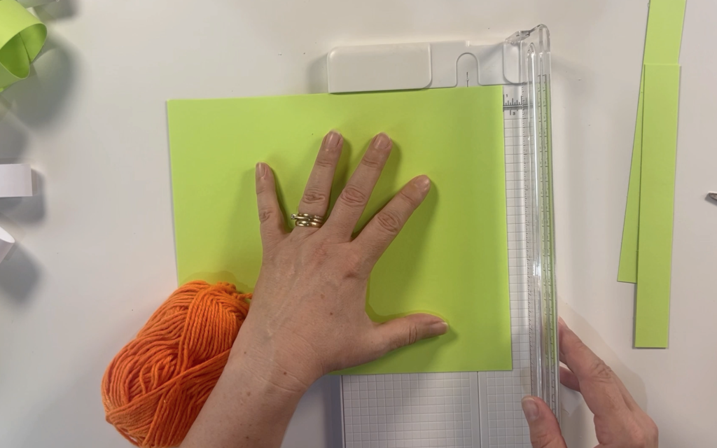 Cutting a sheet of green card into 1 inch thick strips using a paper cutter