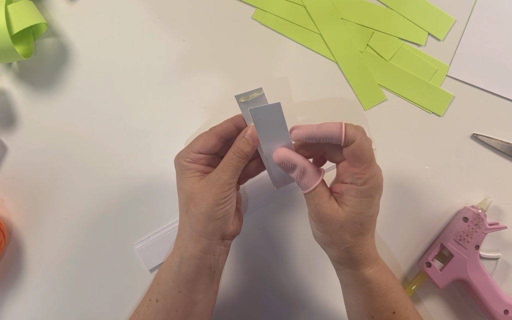 Adding hot glue and folding the card over to make a loop