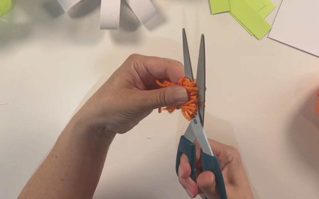 Cutting through the wool loops of the pompom