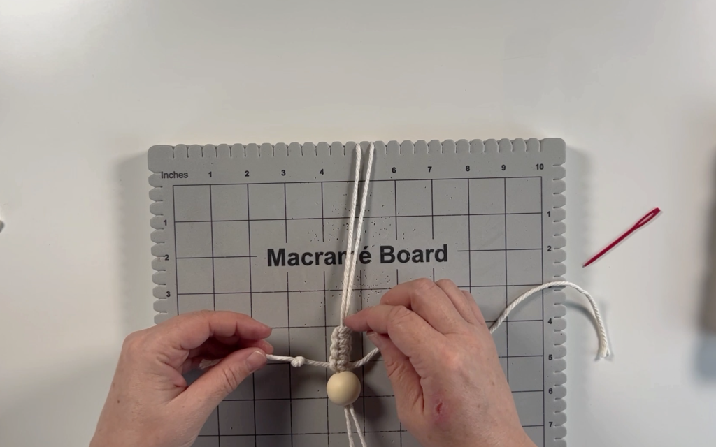 4 square knots being pushed up towards the wooden bead