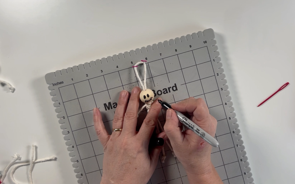 Drawing the skeleton face onto the wooden bead with a sharpie pen.