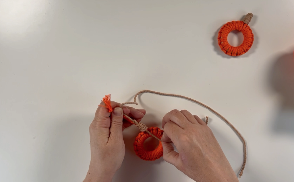 Making a gathering knot around the 2 long strands of orange macrame cord
