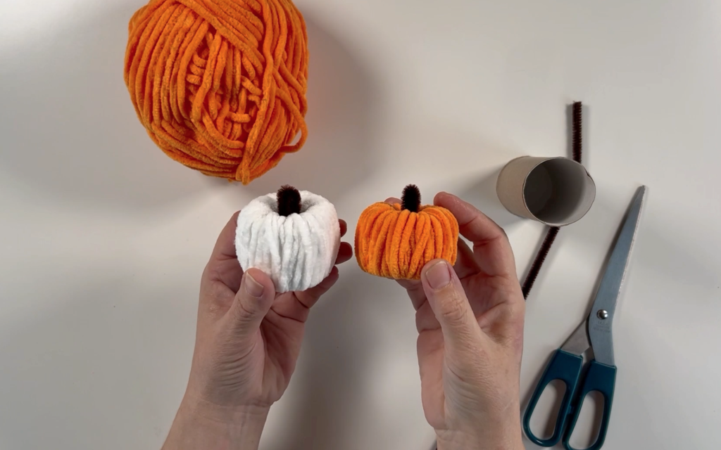 Orange and white yarn covered pumpkins made using toilet roll tubes. 