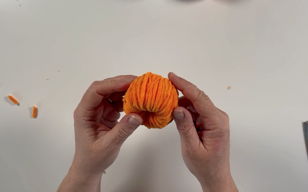 A toilet tube totally covered in orange wool.