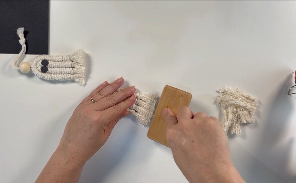 Using a macrame brush to brush the macrame cord